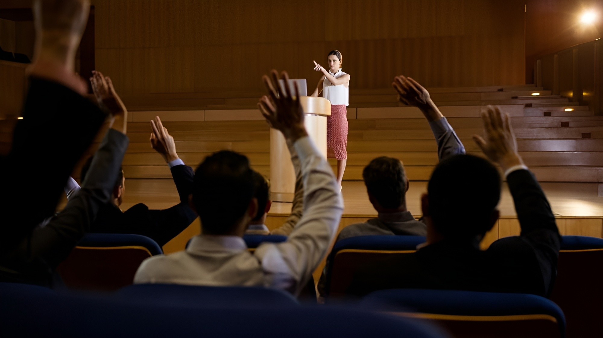 Audience members raising their hands during a presentation
