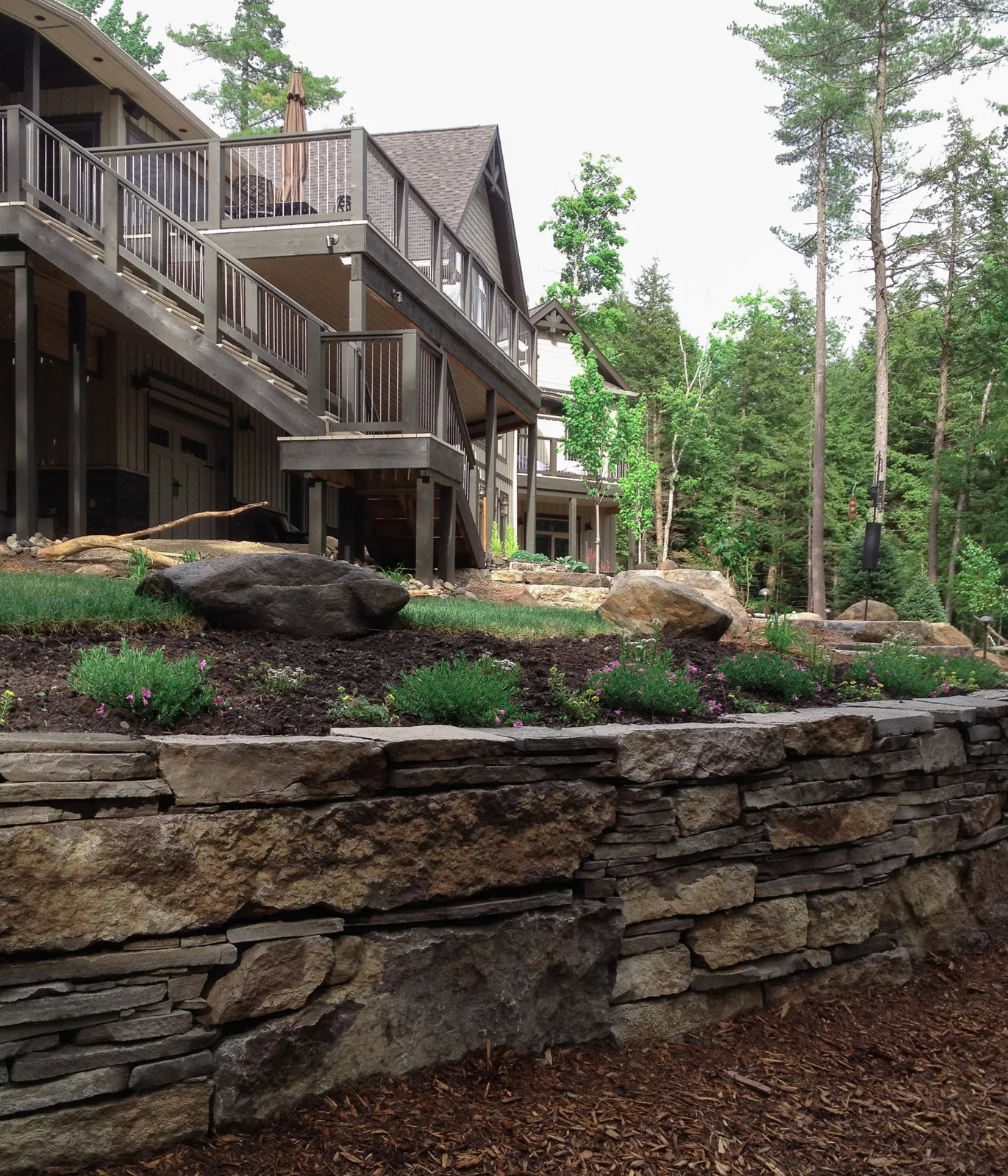 a luxury cottage with custom granite and limestone landscaping and cut stone retaining wall.