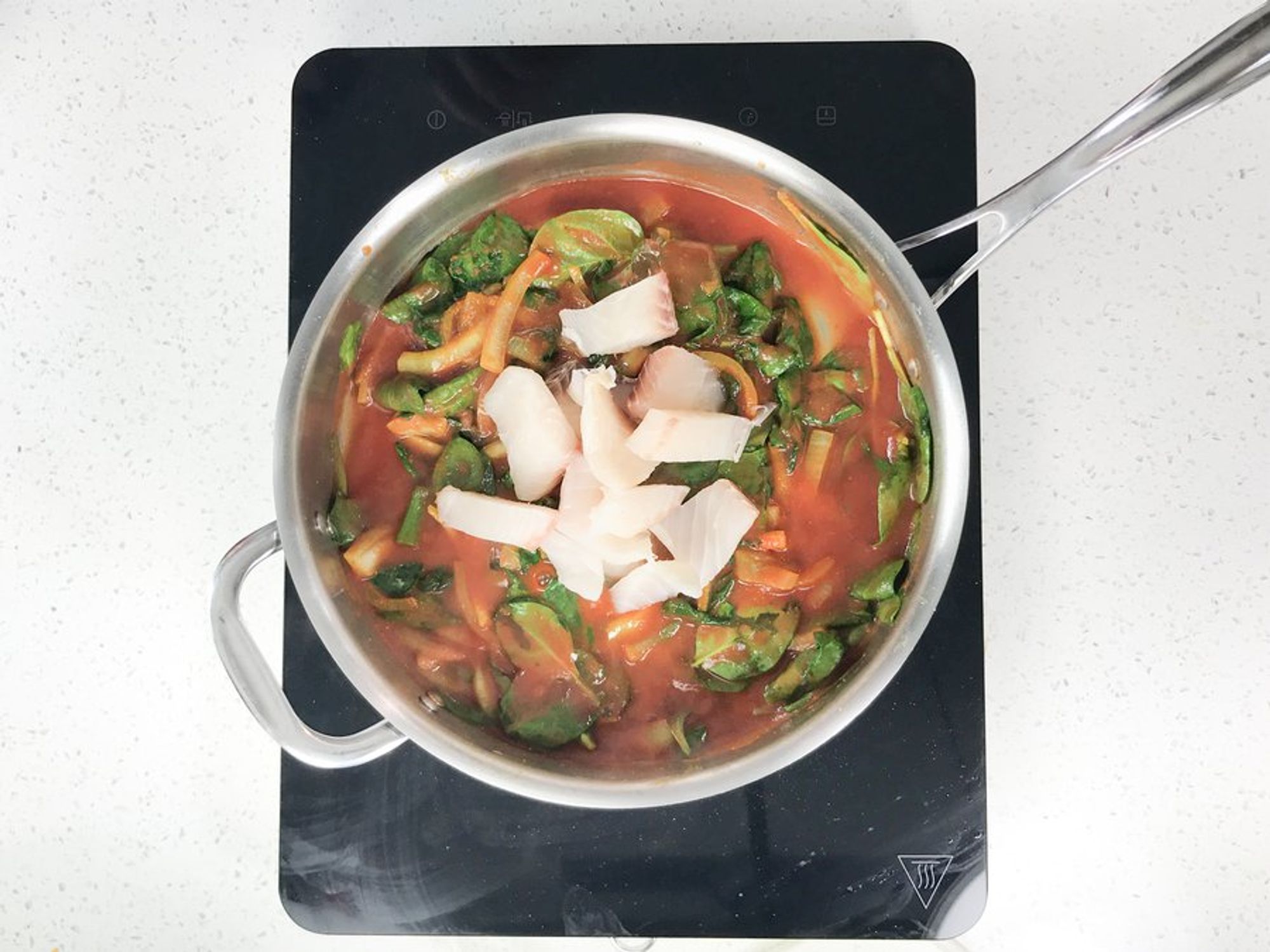 fish curry being cooked in a deep skillet