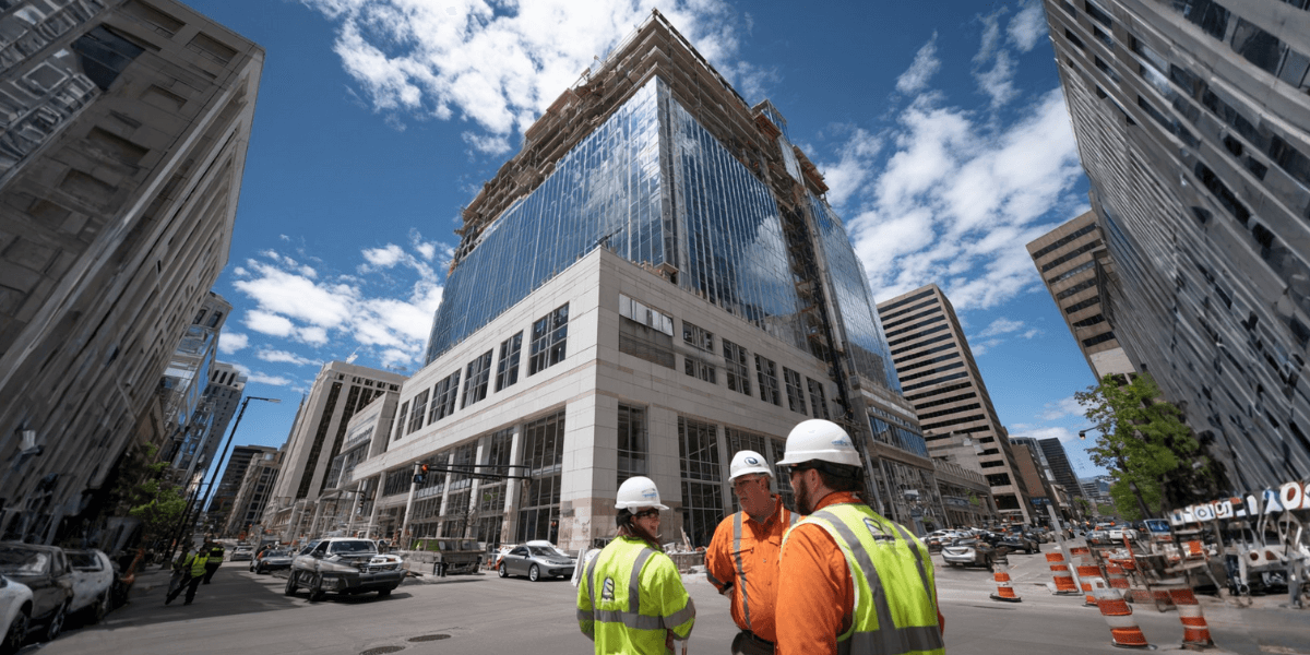 Construction workers discuss progress in front of a tall commercial building under construction, highlighting PBR Capital's fast financing solutions."