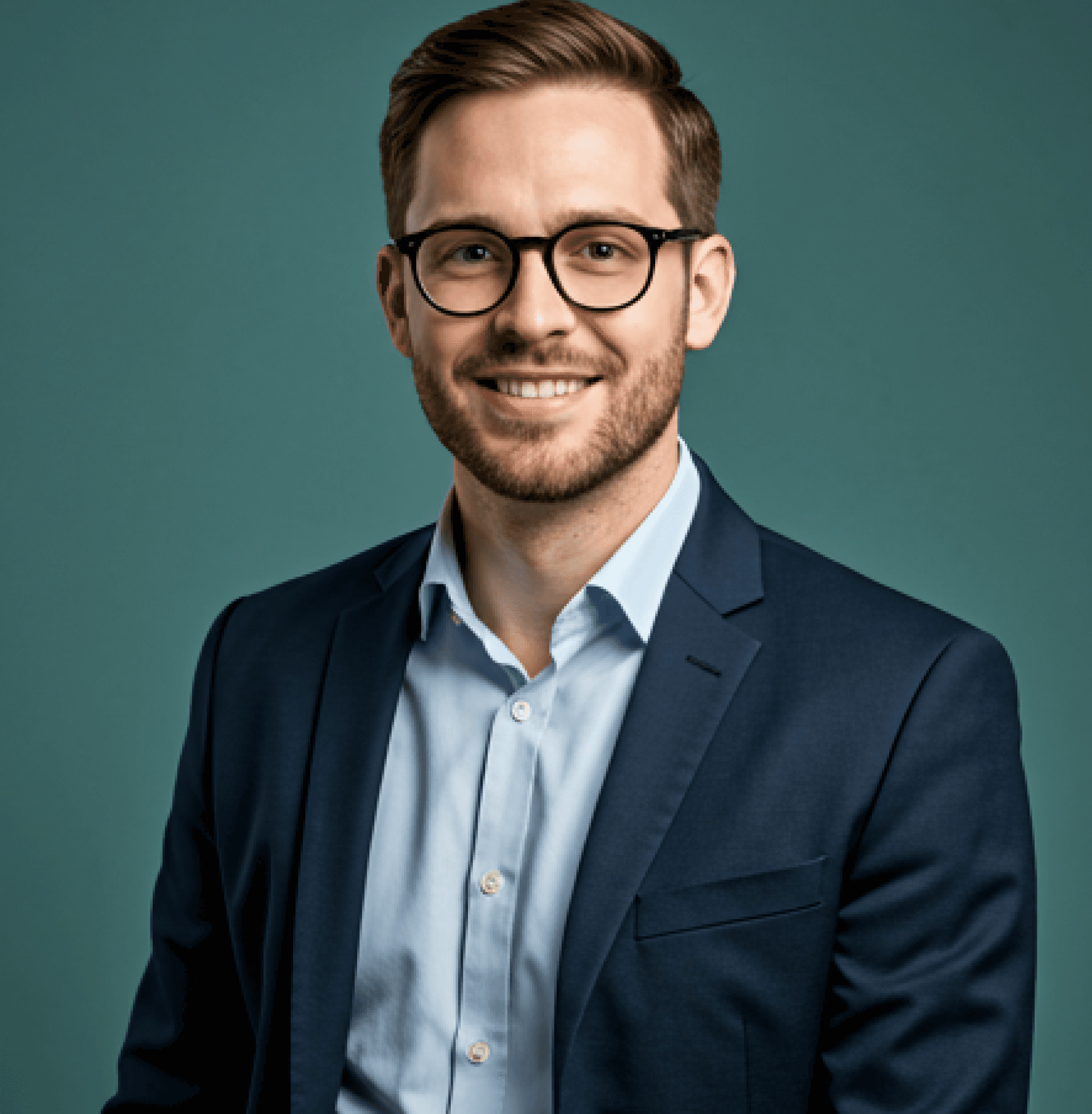 A smiling individual wearing glasses and a blazer stands against a solid background, looking confident and approachable.