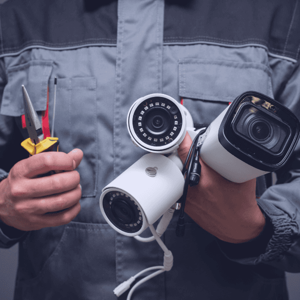 Video security installer holding cameras and tools