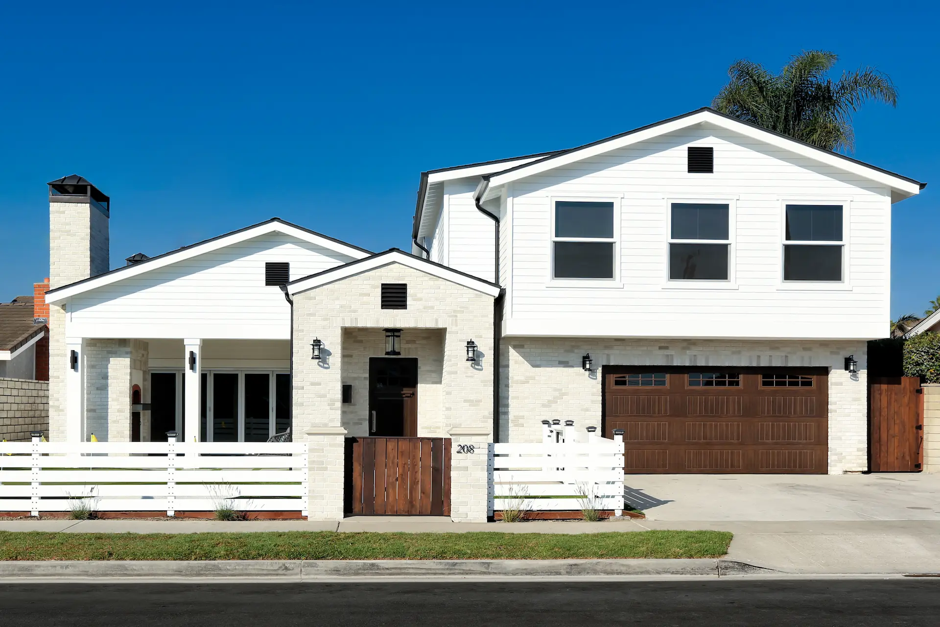 Front view of American Farmhouse 2 story home with white siding and black decorative trim. Photo by Chris Darnall.