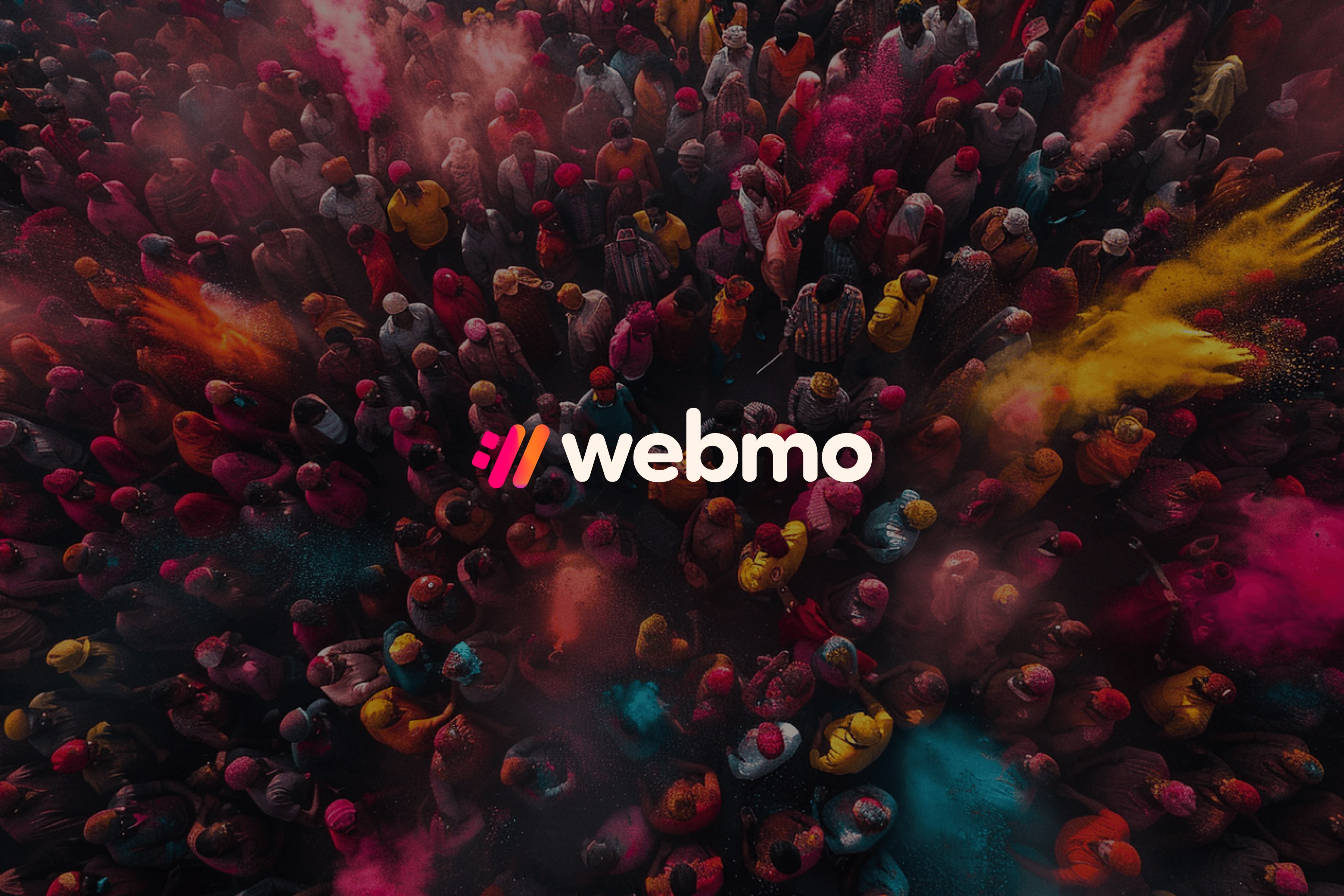 An overhead drone photography of a bunch of people enjoying and celebrating the Indian holiday of Holi.   Dark background overlay and the full WebMO logo lockup and logo icon that is colorful and the Holi-inspired mesh gradient for the logo icon. 