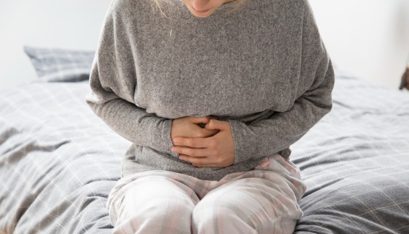 Жінка тримає себе руками за живіт