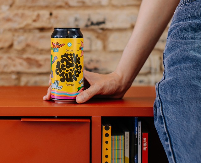 Hand resting on a colourful 'Get the creative juices flowing' beer can.
