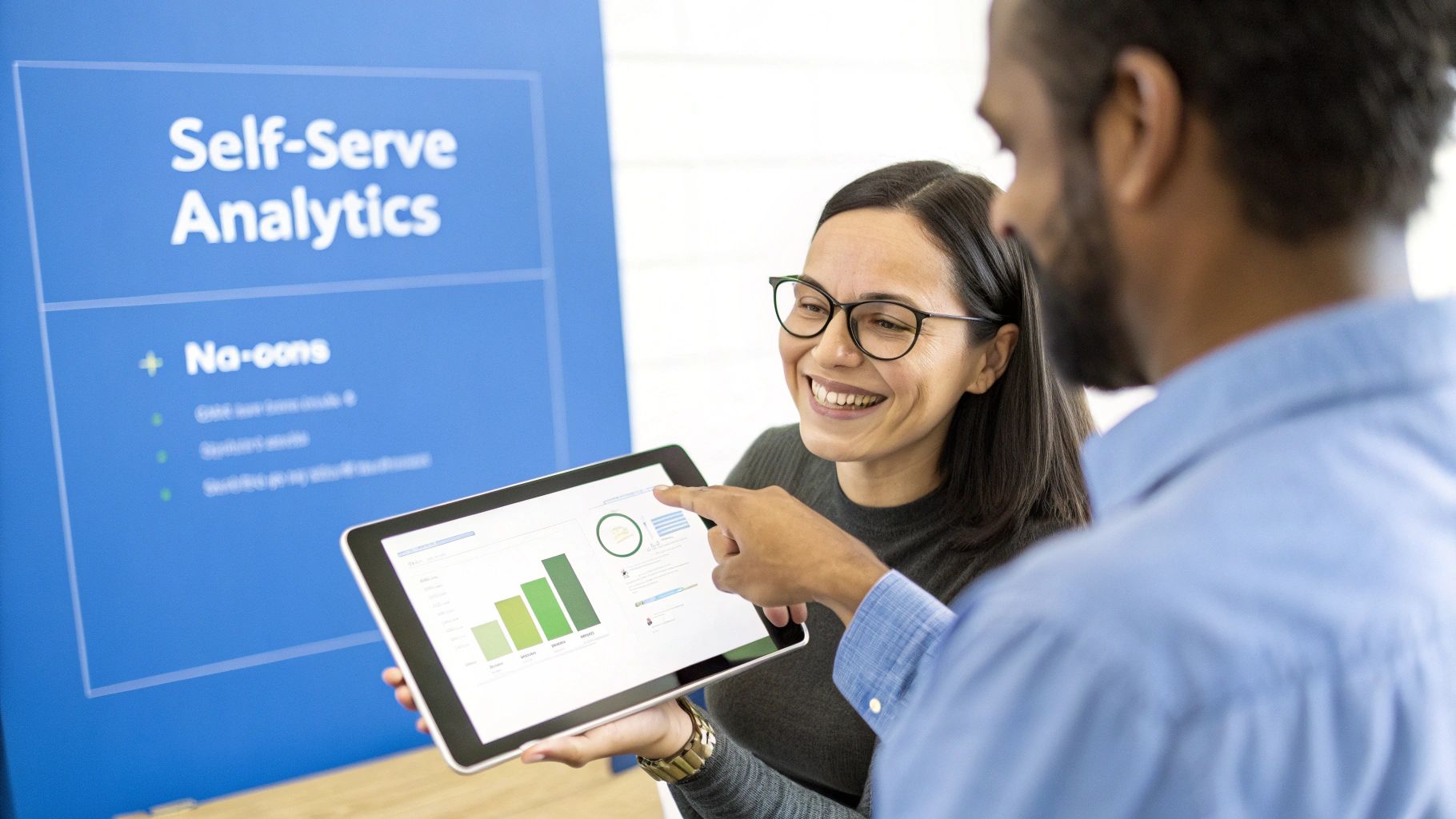 Two colleagues collaboratively discussing data analytics on a tablet, with a 'Self-Serve Analytics' banner in the background.