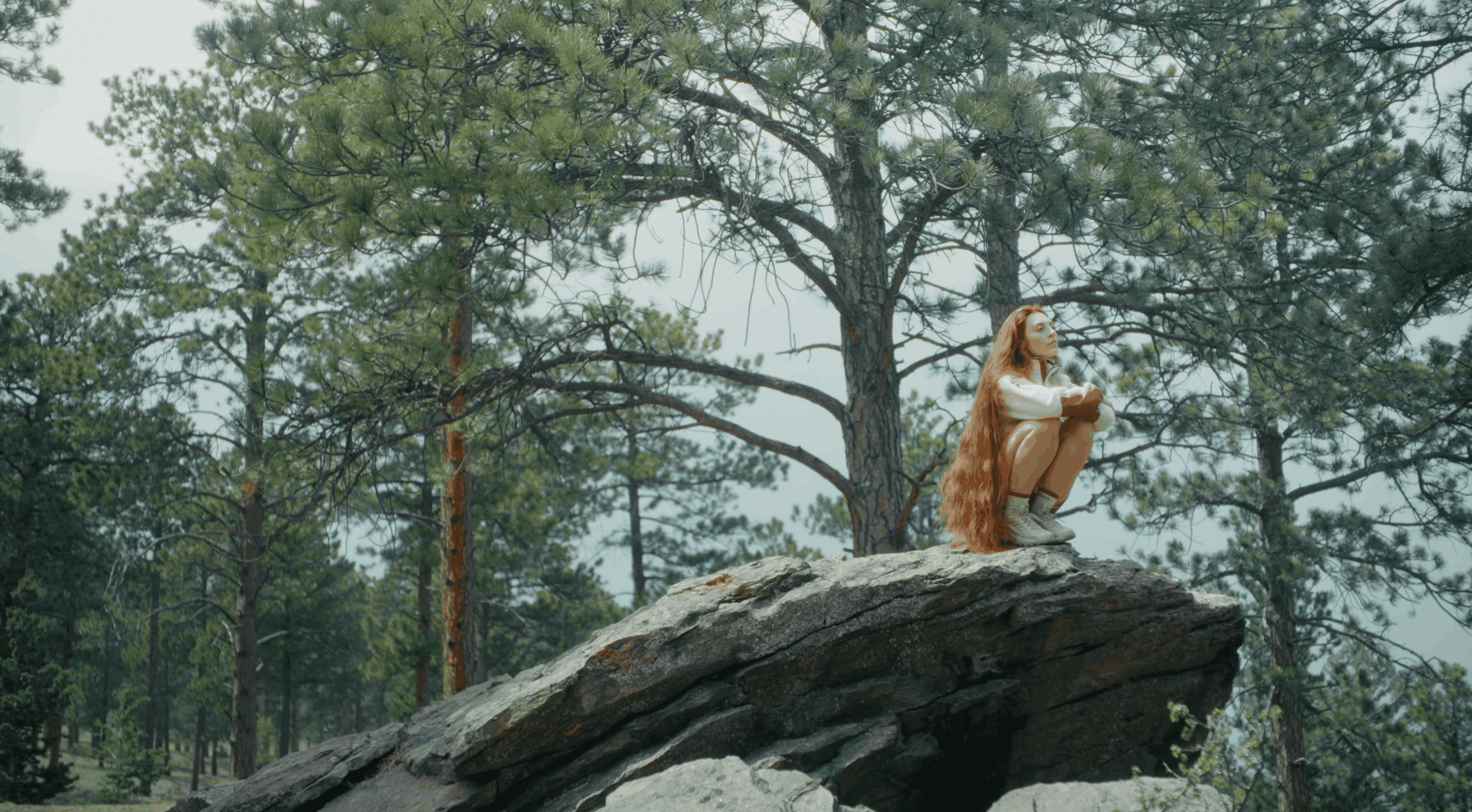 model wearing halfdays outerwear sitting on a rock in the colorado mountains
