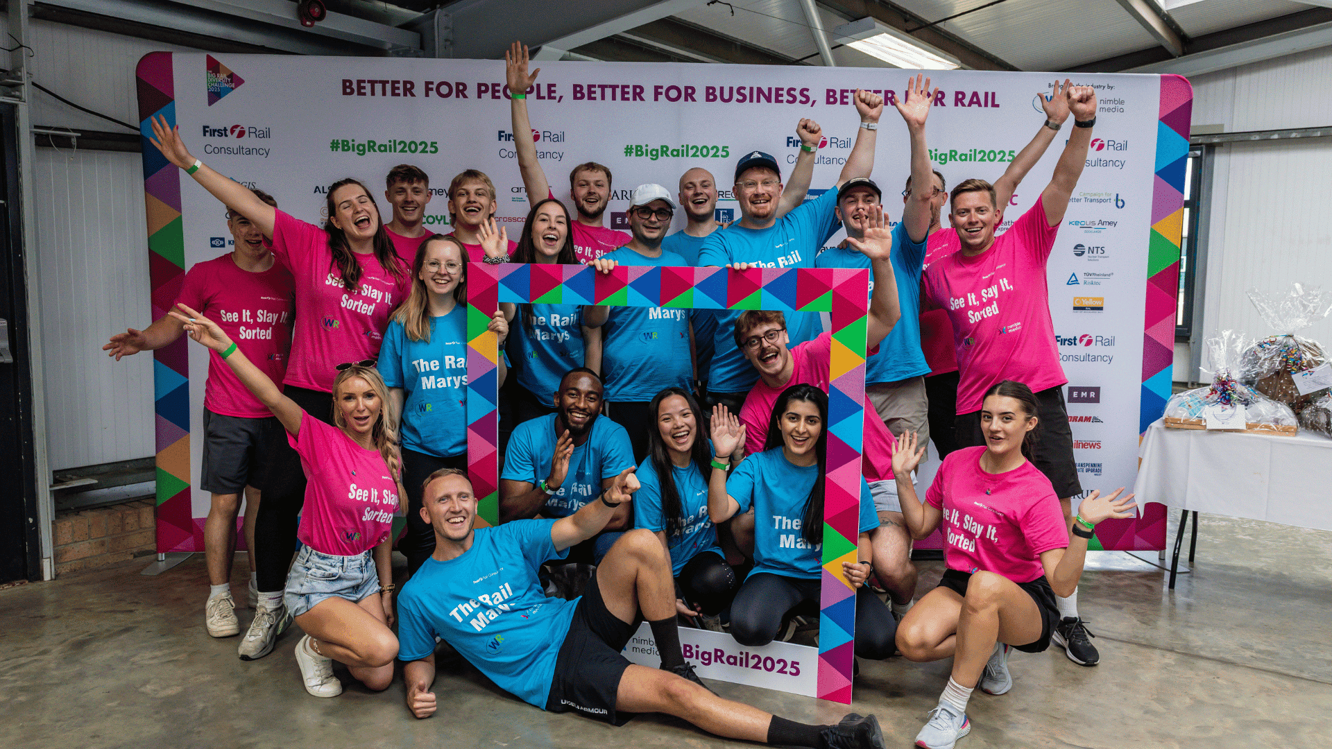 Outdoor team-building event with participants wearing matching blue shirts, taking part in inflatable obstacle courses and games, smiling and cheering, with the words 'ENTER A TEAM' in large bold white and green text across the image.