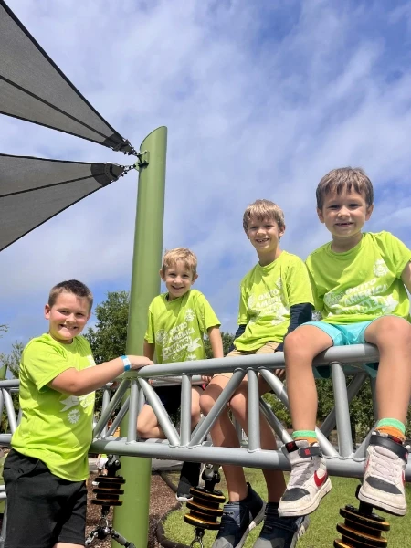 Four boys sitting on a jungle gym.
