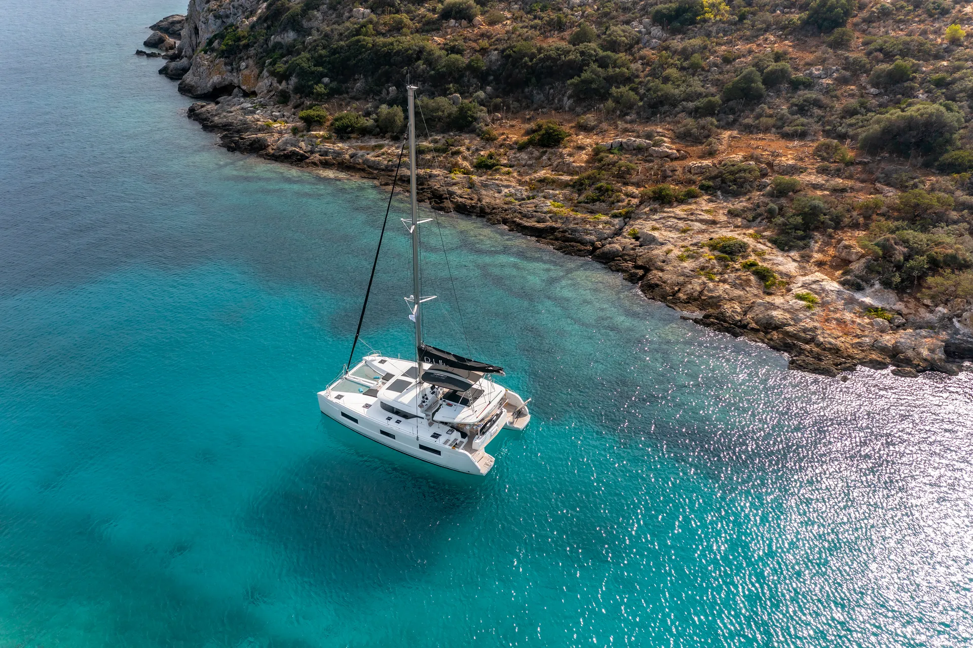 White Rock 36 speedboat with captain at helm cruising calm blue waters near Paros coastline with hills in background.