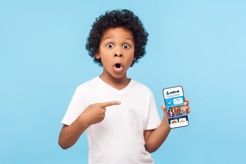 Young boy pointing at his phone with a shocked expression.