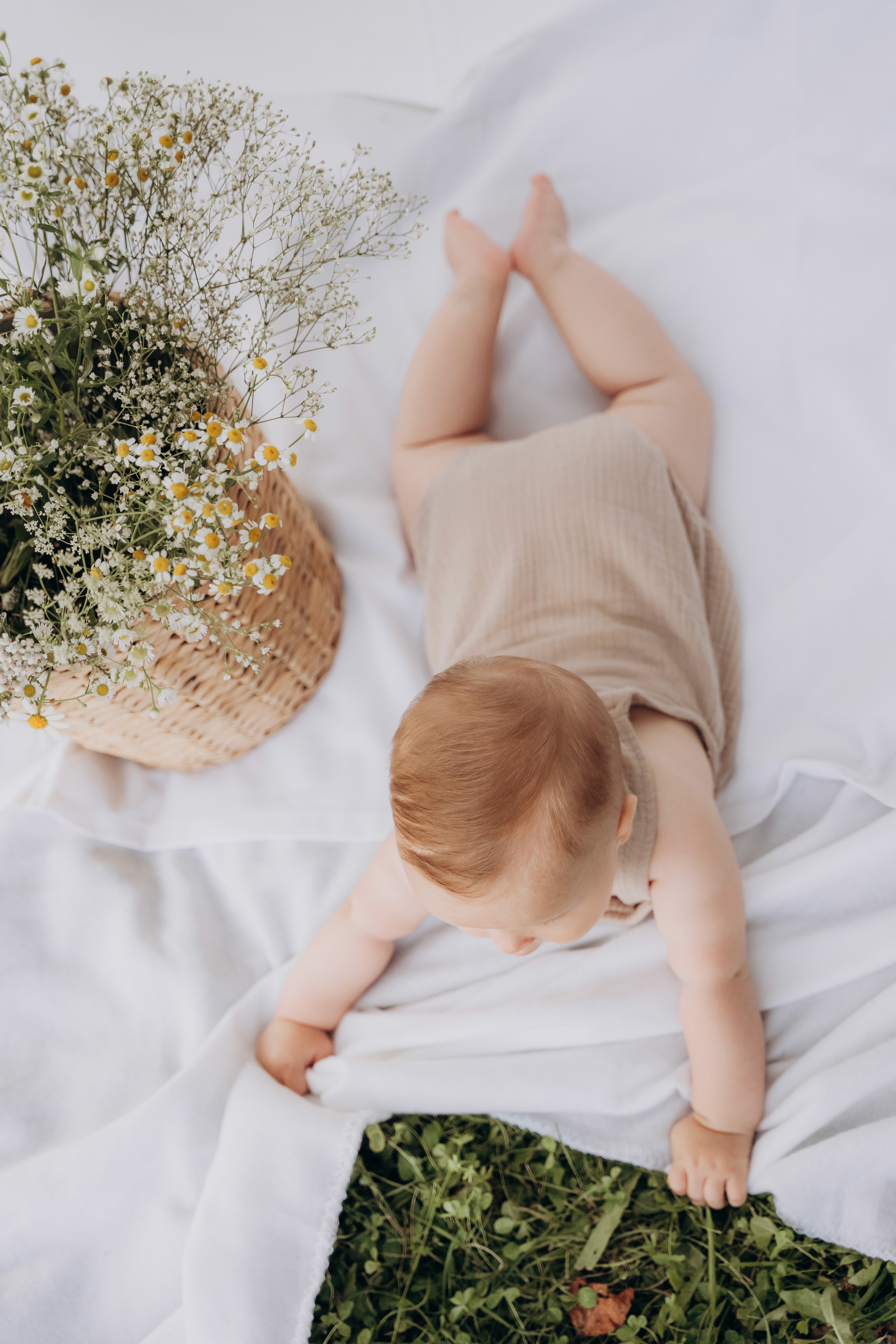 Babyfotografie Outdoor in Bogen – Baby liegt auf einer Decke im Grünen bei natürlichem Fotoshooting.