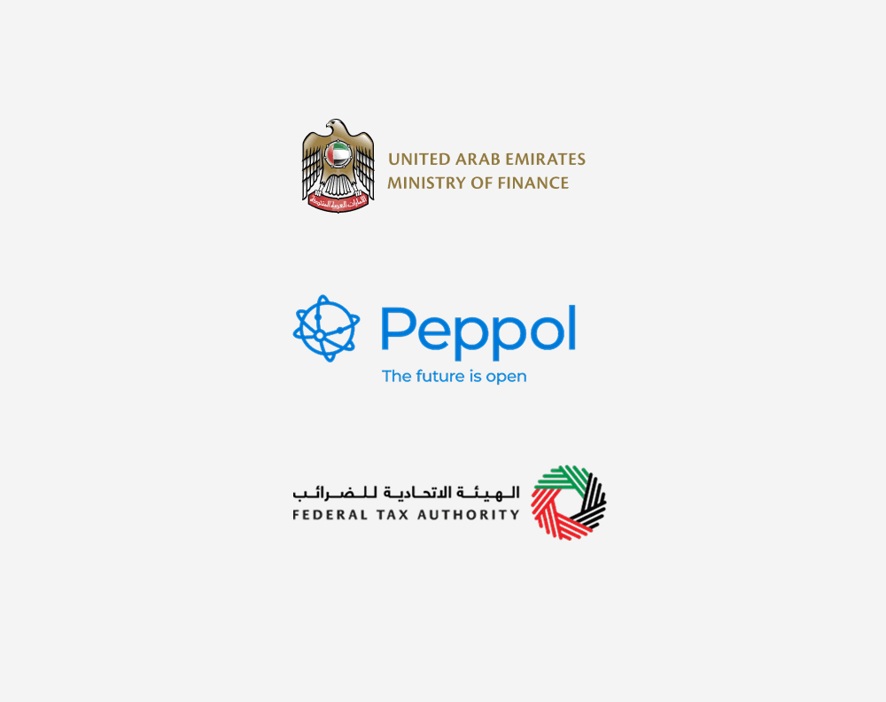 A young person with curly hair smiles at the camera while sitting in front of a laptop against a dark background.