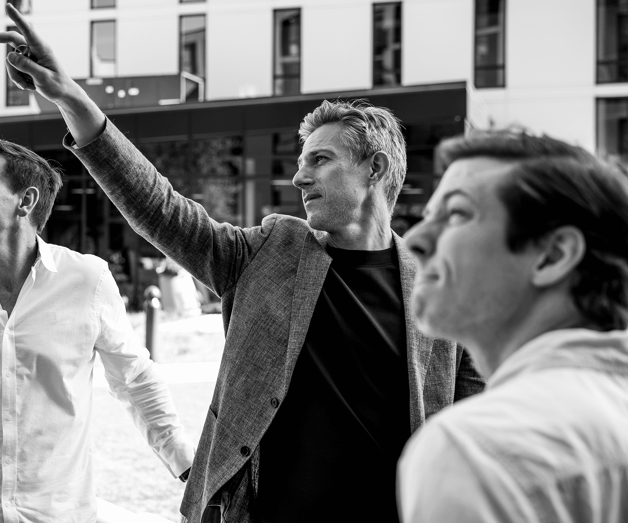 Black and white image of people working at a table with laptops, showing hands gesturing during discussion of digital content displayed on screens, with fabrica® logo in the corner.