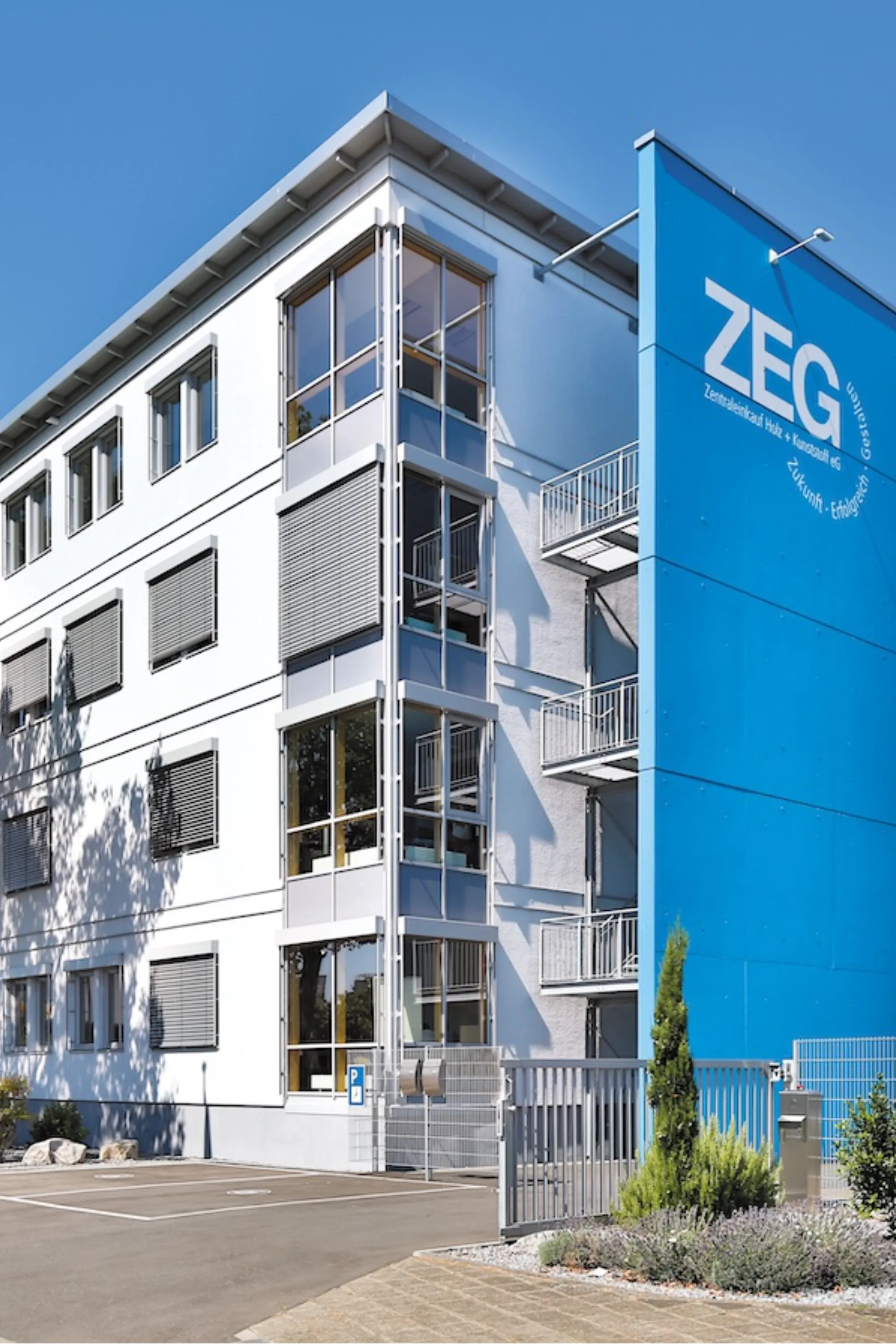 ZEG-Gebäude mit blauer Fassade,Fenstern und Balkonen vor blauem Himmel.