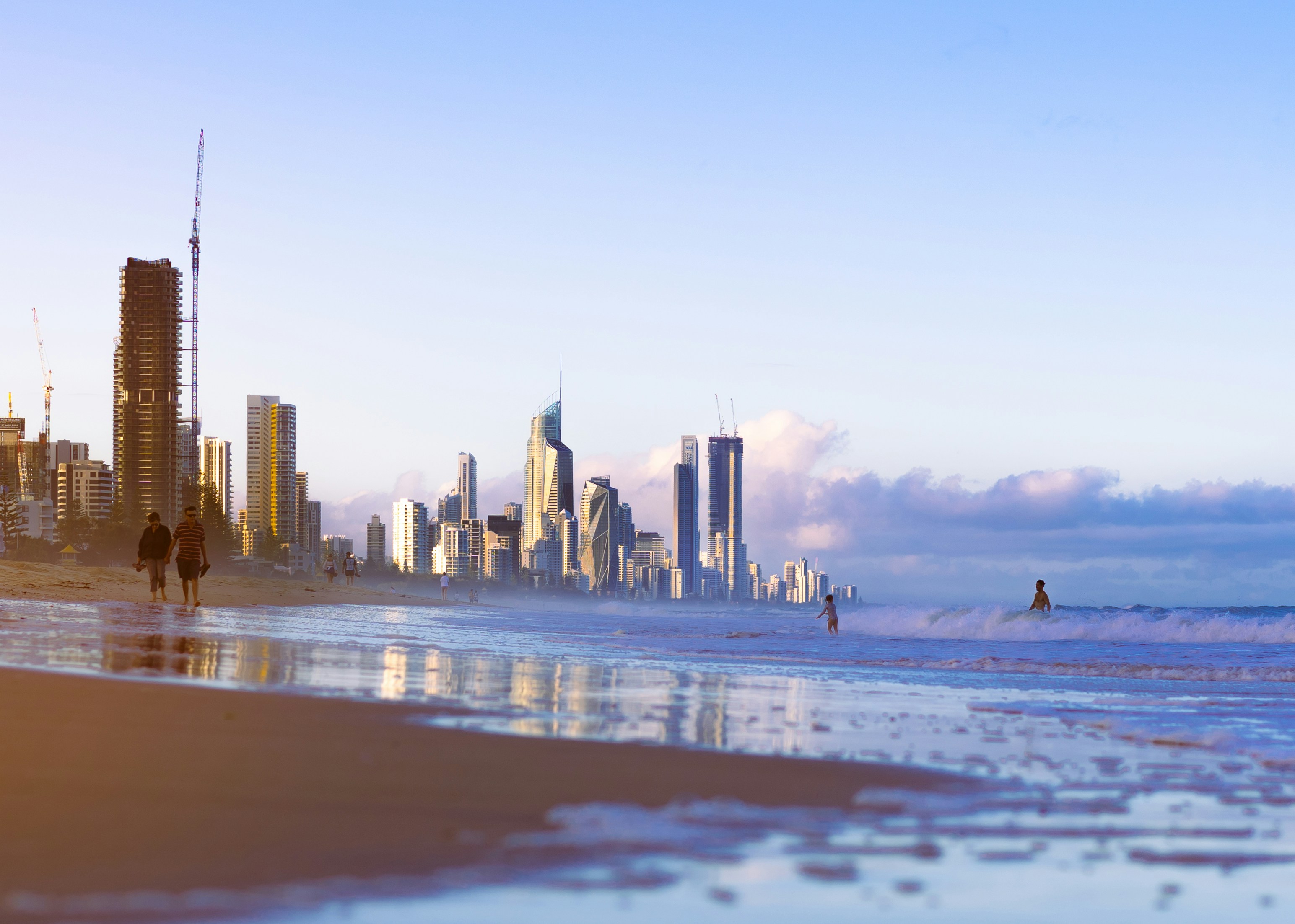 people walking on the beach in front of a city