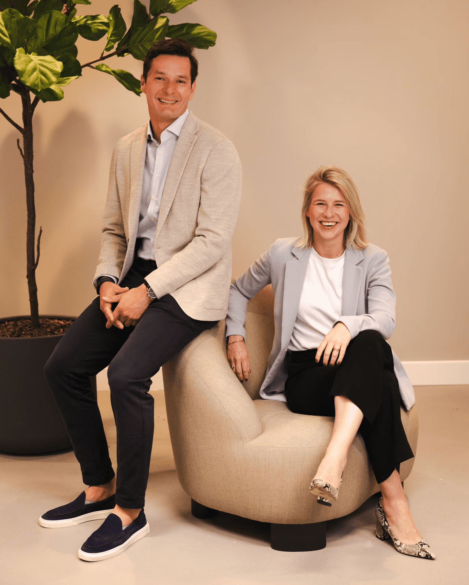A modern restaurant with a teal coffered ceiling, white curtains, large windows, dark leather chairs, wooden tables, and a white dome lamp on a marble counter.