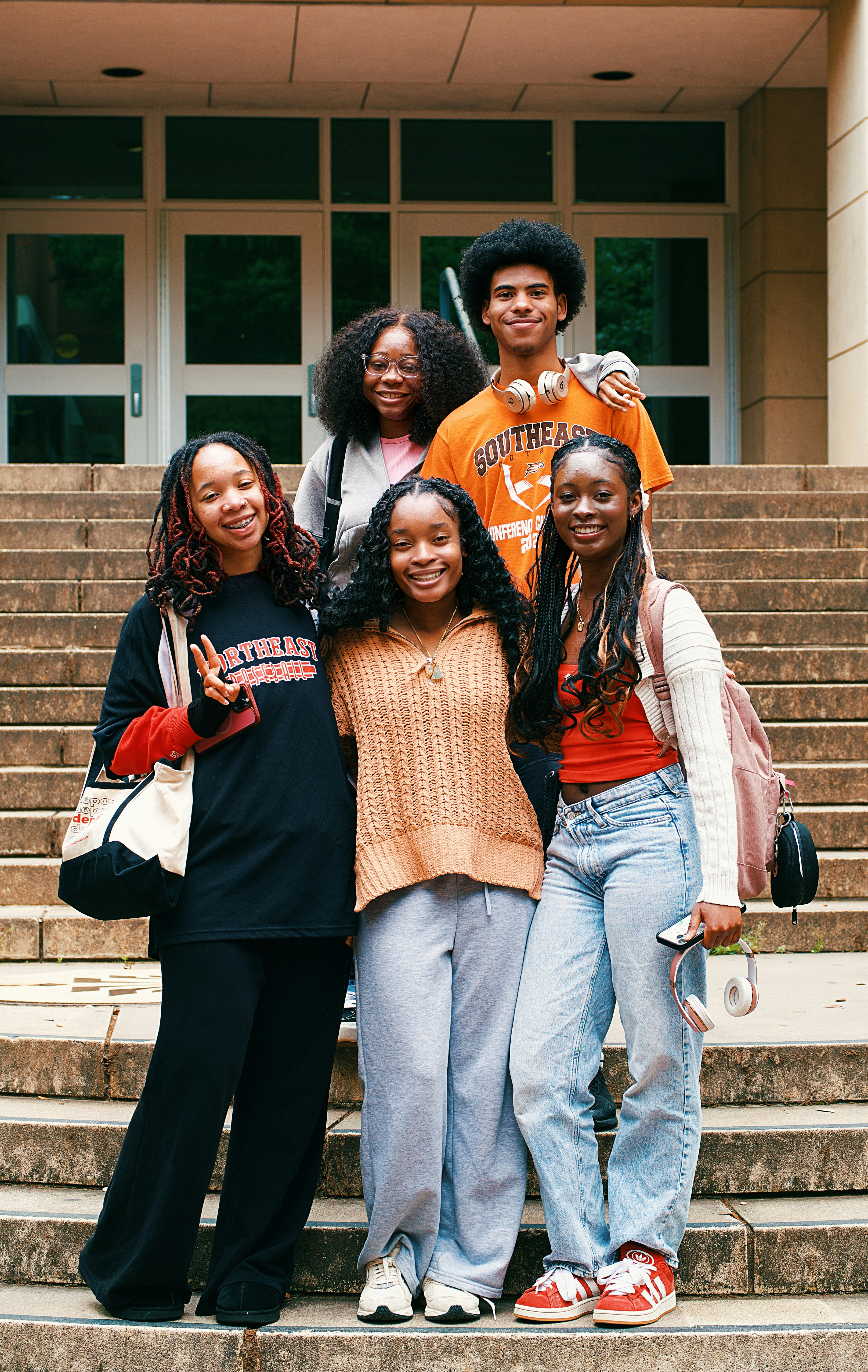 A group of smiling friends pose on some steps.