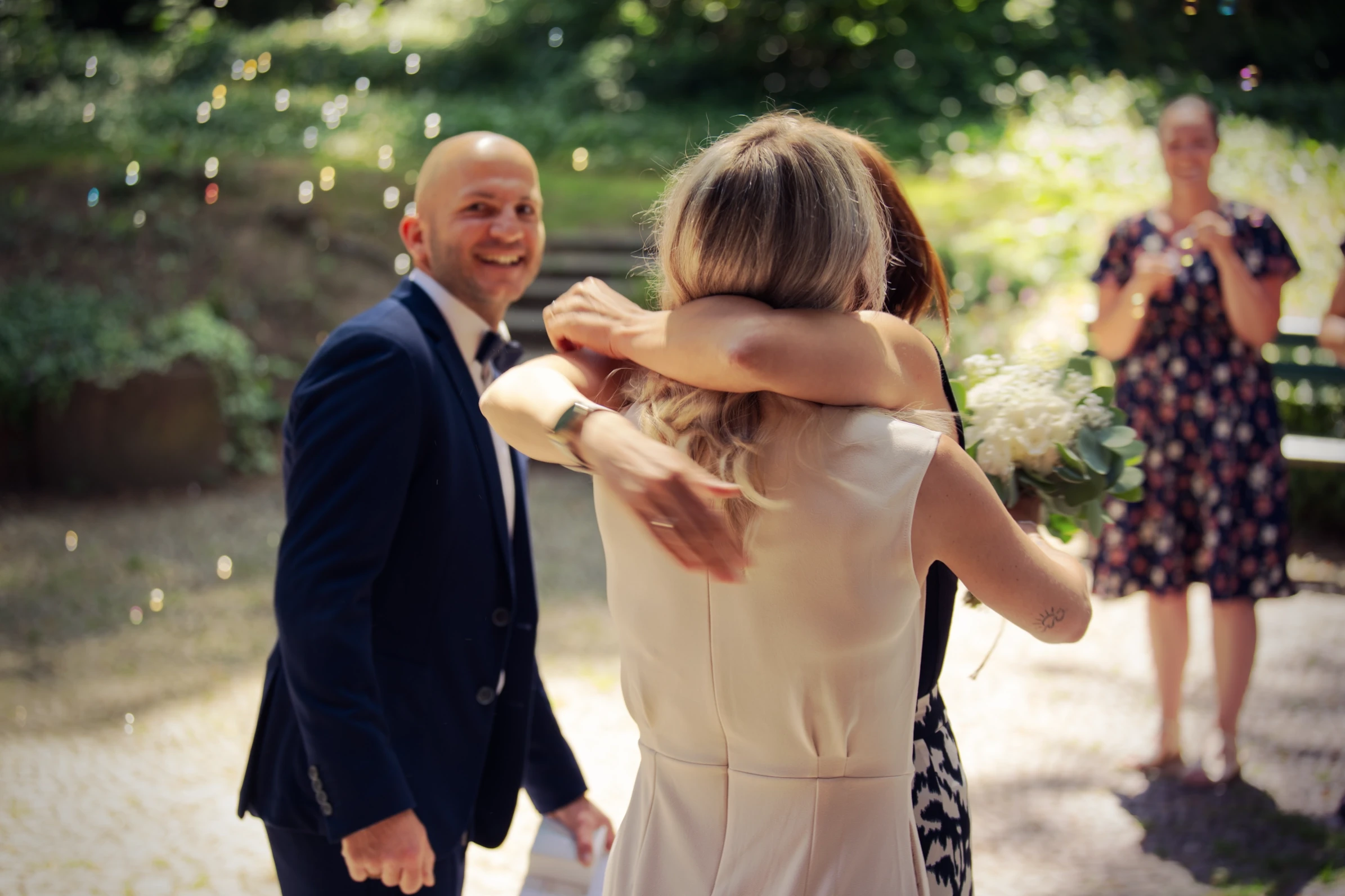Brautpaar begrüßt Gäste bei emotionaler Sommerhochzeit im Grünen mit cineastischem Bokeh und natürlichem Licht.