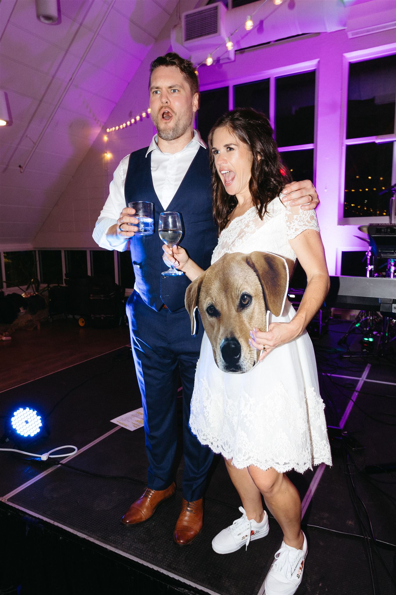 Couple enjoying the reception with a dog cutout beneath purple party lights.