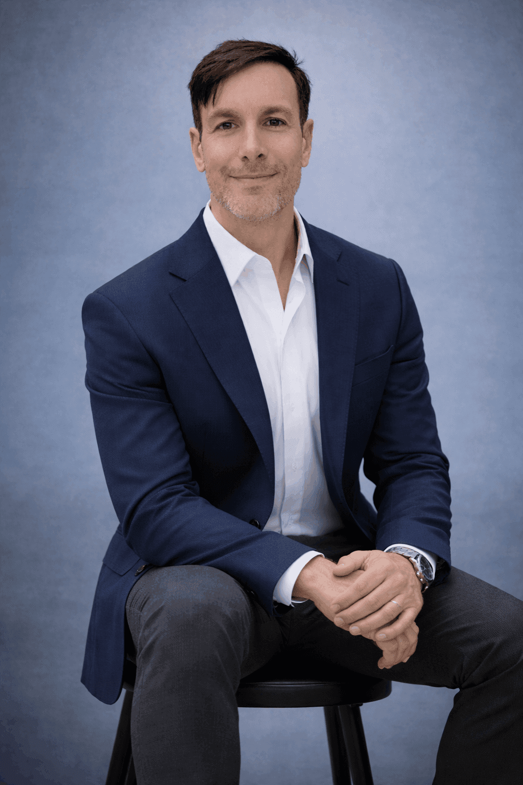 Professional portrait of Anthony Hauser, Managing Partner of Blue Ridge Partners, seated in business attire against blue backdrop.