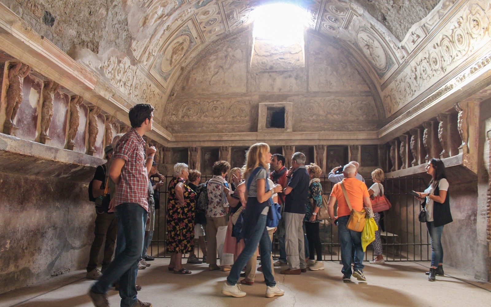Tourists with guide exploring ancient ruins of Pompeii, Italy.