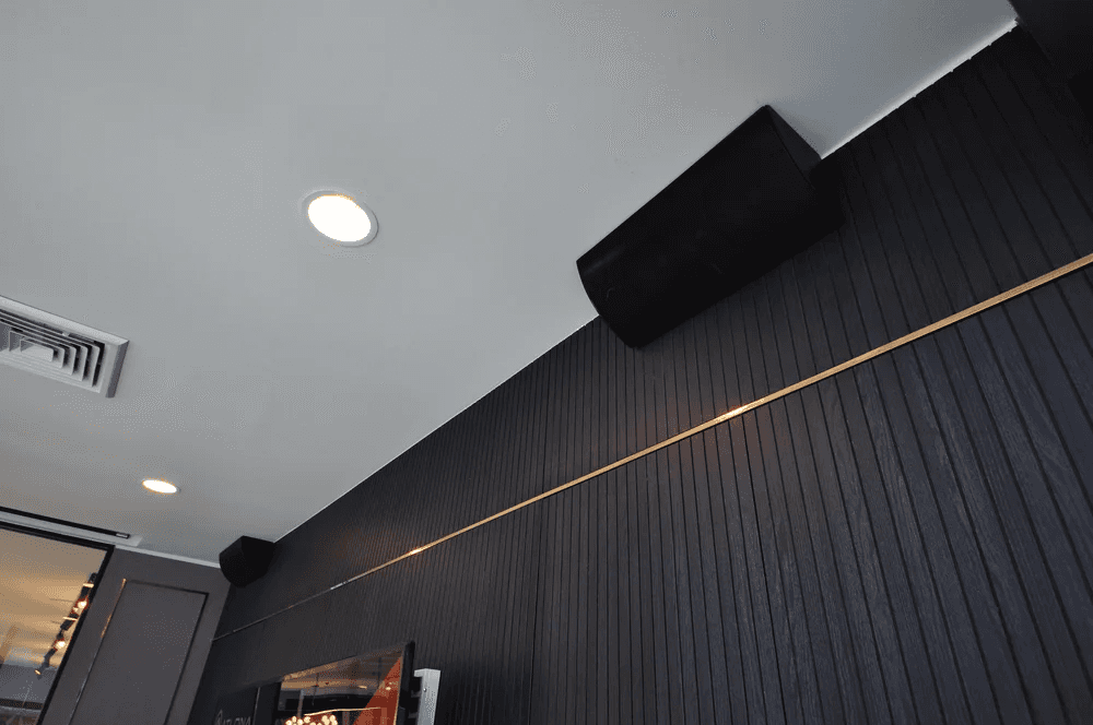 Ceiling speakers and dark wood paneling.