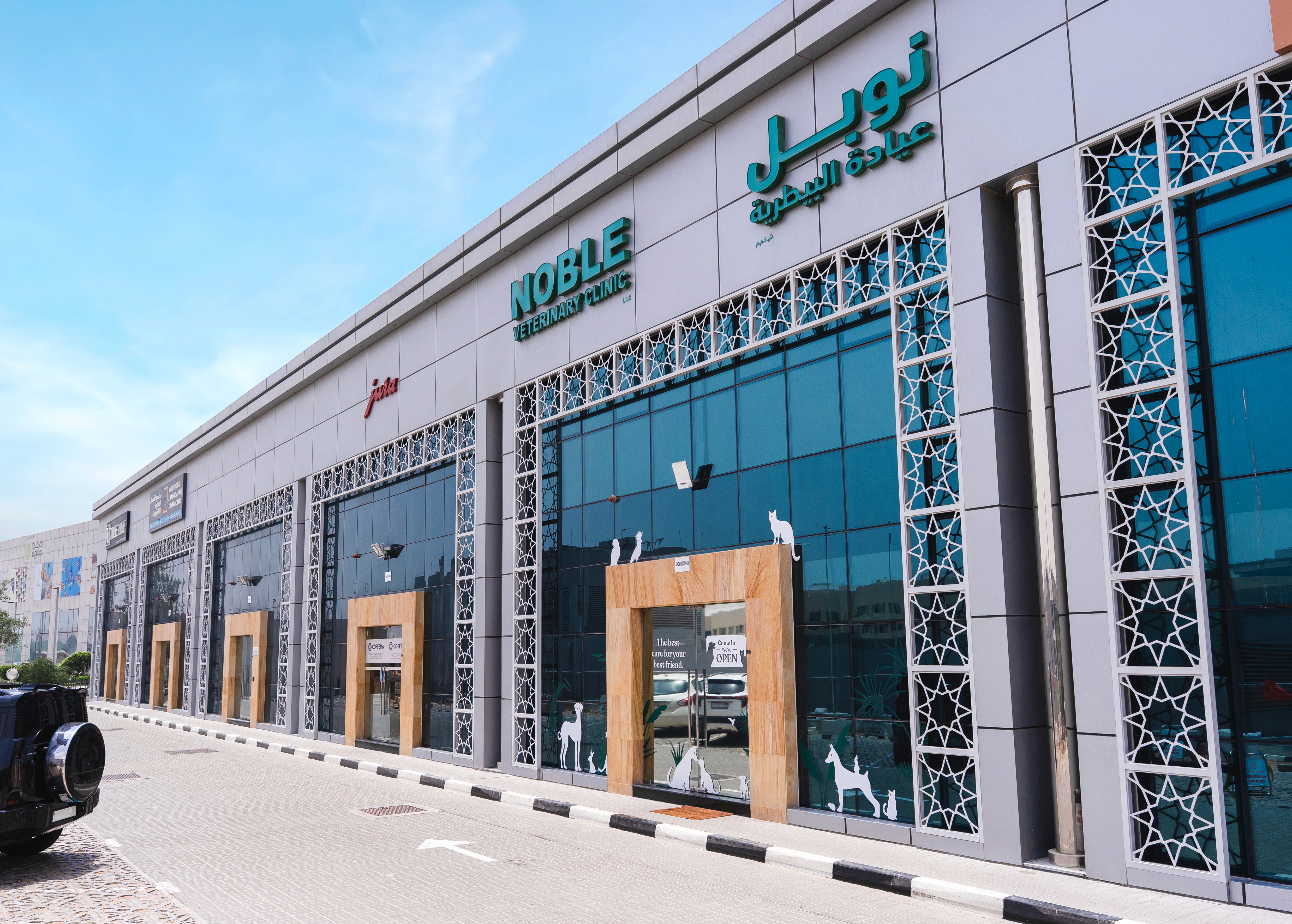 The front of Noble Veterinary Clinic in DIP, Dubai. Our vet clinic features glass doors and windows with reverse silhouettes of pets on the windows surrounding the doors.
