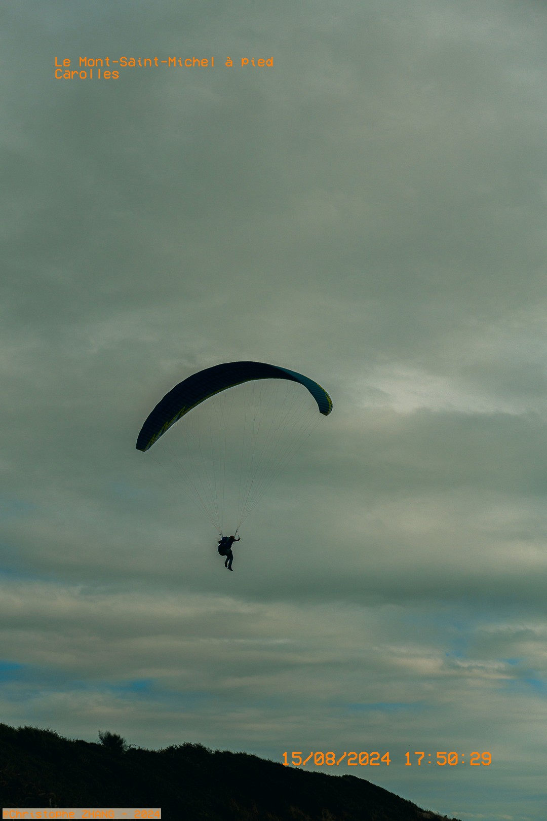 Parapentiste au-dessus des falaises, randonnée et vue vers le Mont Saint‑Michel.