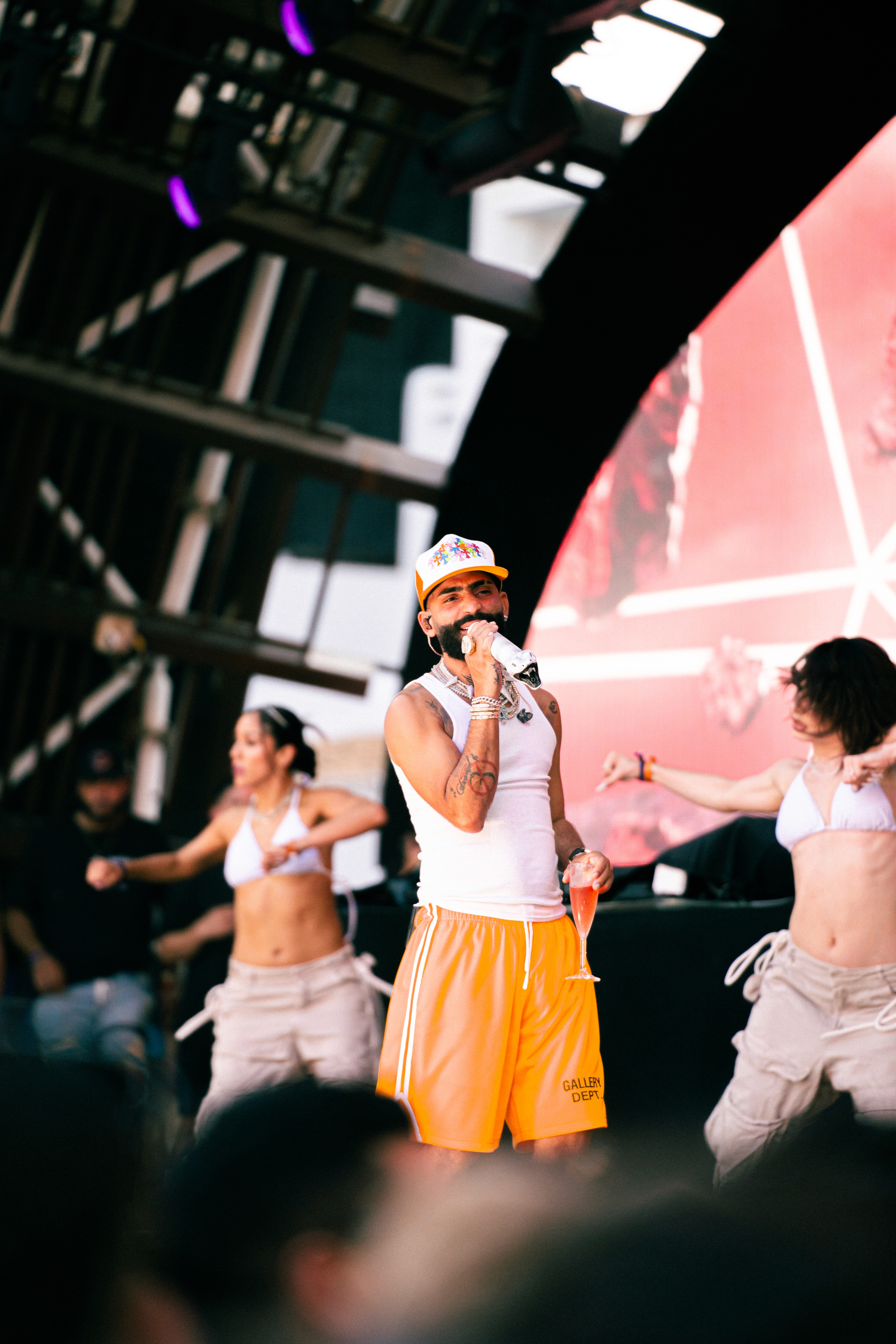 A woman wearing a shiny coat stands in focus, while a blurred background creates a sense of movement.
