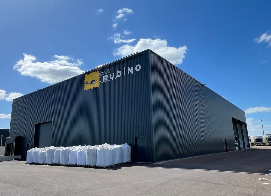 Bâtiment industriel terminé avec bardage sombre et zone de stockage extérieure.