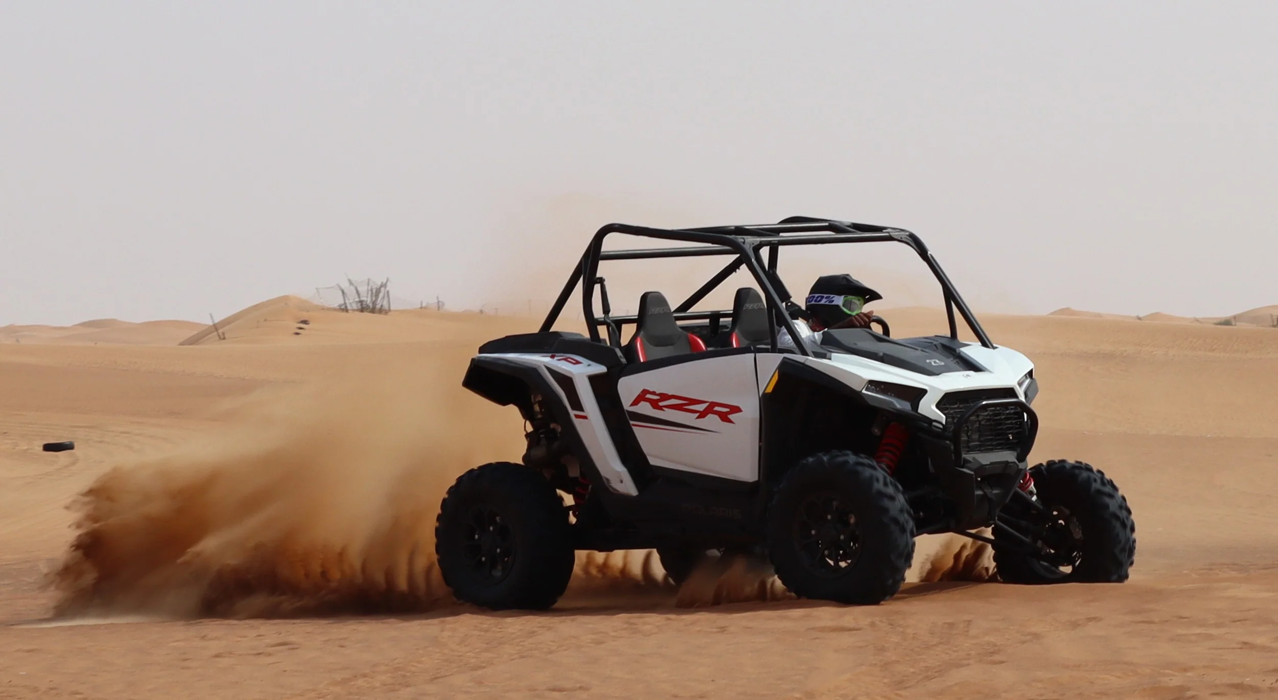 Polaris RZR 1000cc XP buggy driving through sand dunes during a Dubai desert safari with Dune Quest Tours