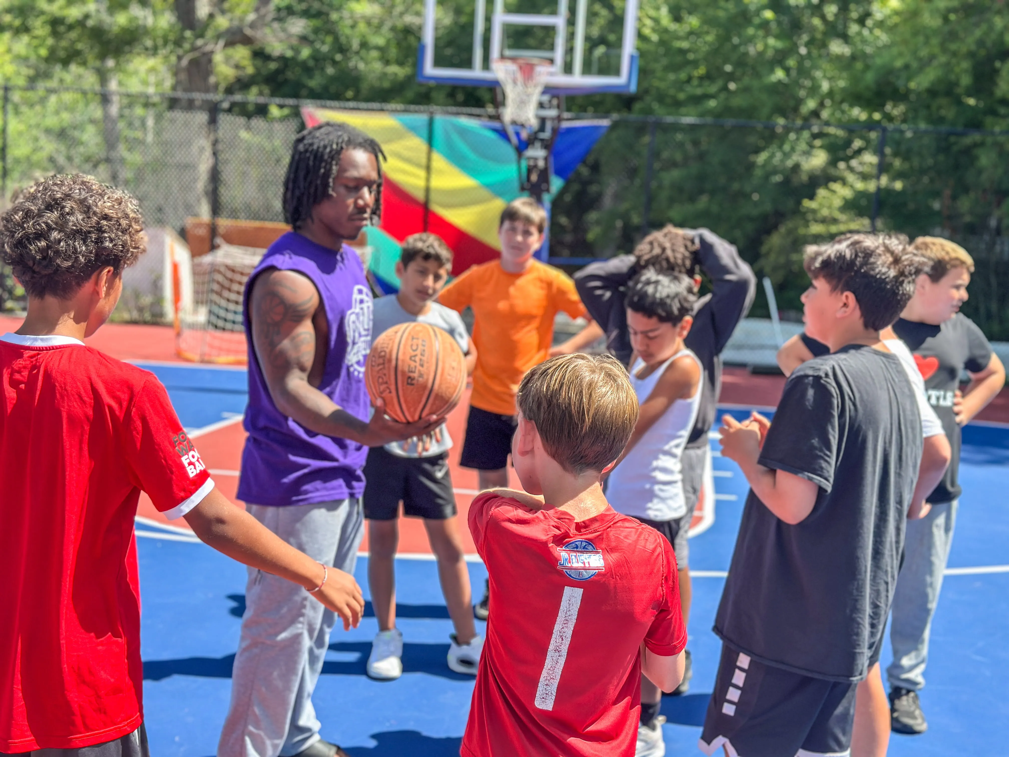 Basketball coach talking to a group of campers on the court