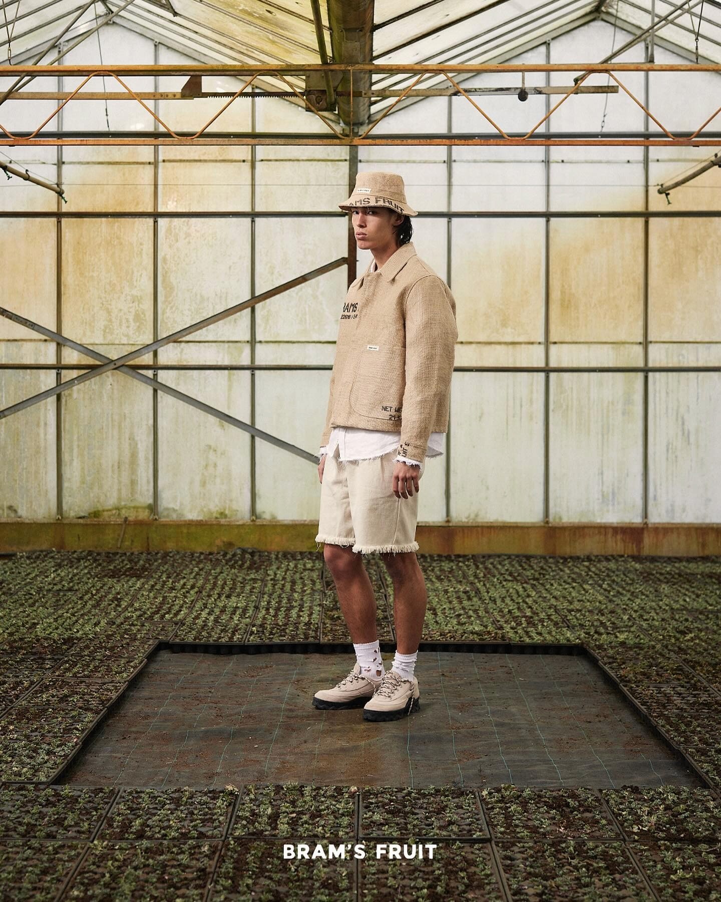 Extrait du lookbook Brams Fruit, le mannequin dans une serre porte un blouson beige, un short et un bob beige