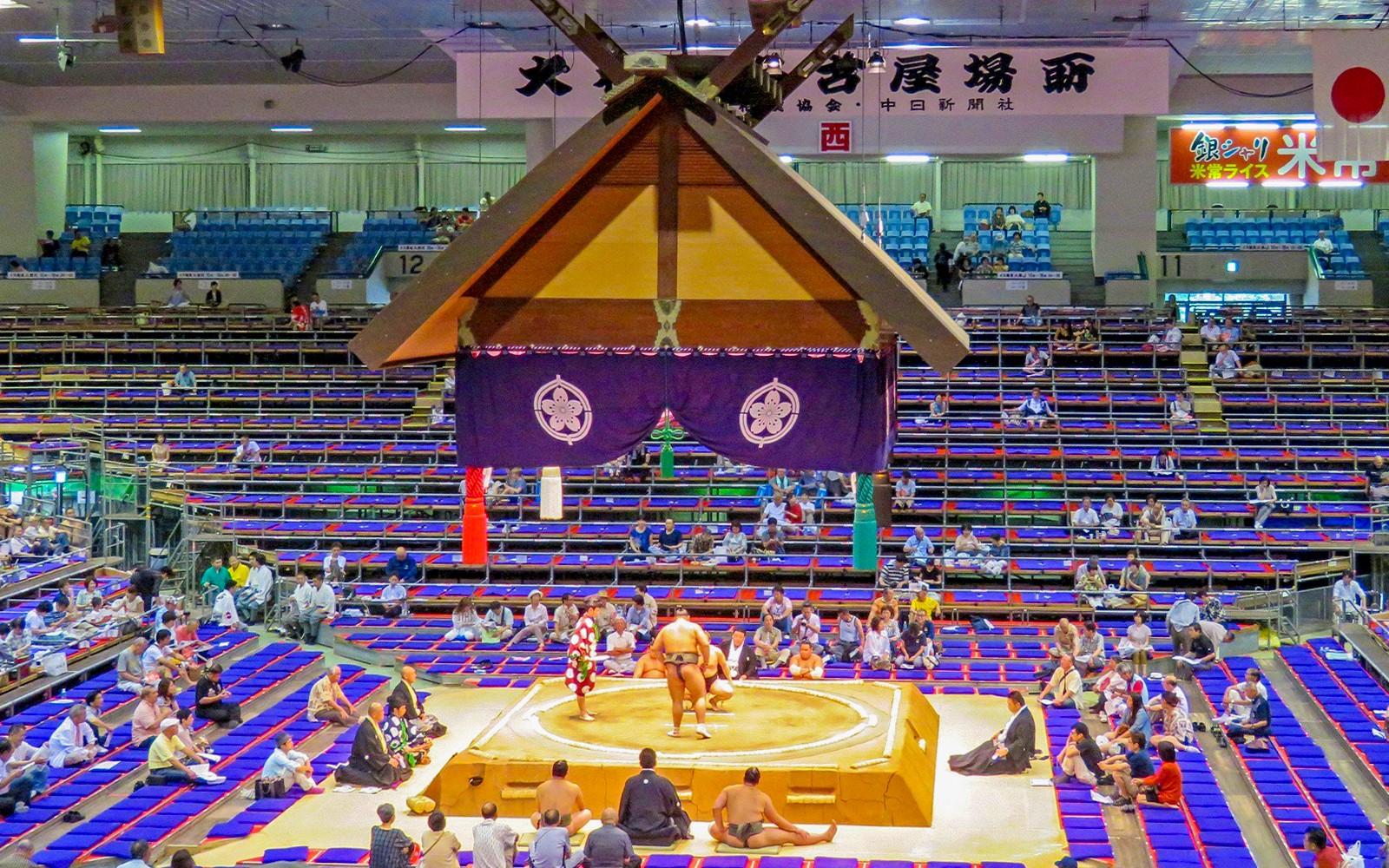 Sumo wrestlers competing in a Fukuoka arena during a tournament.
