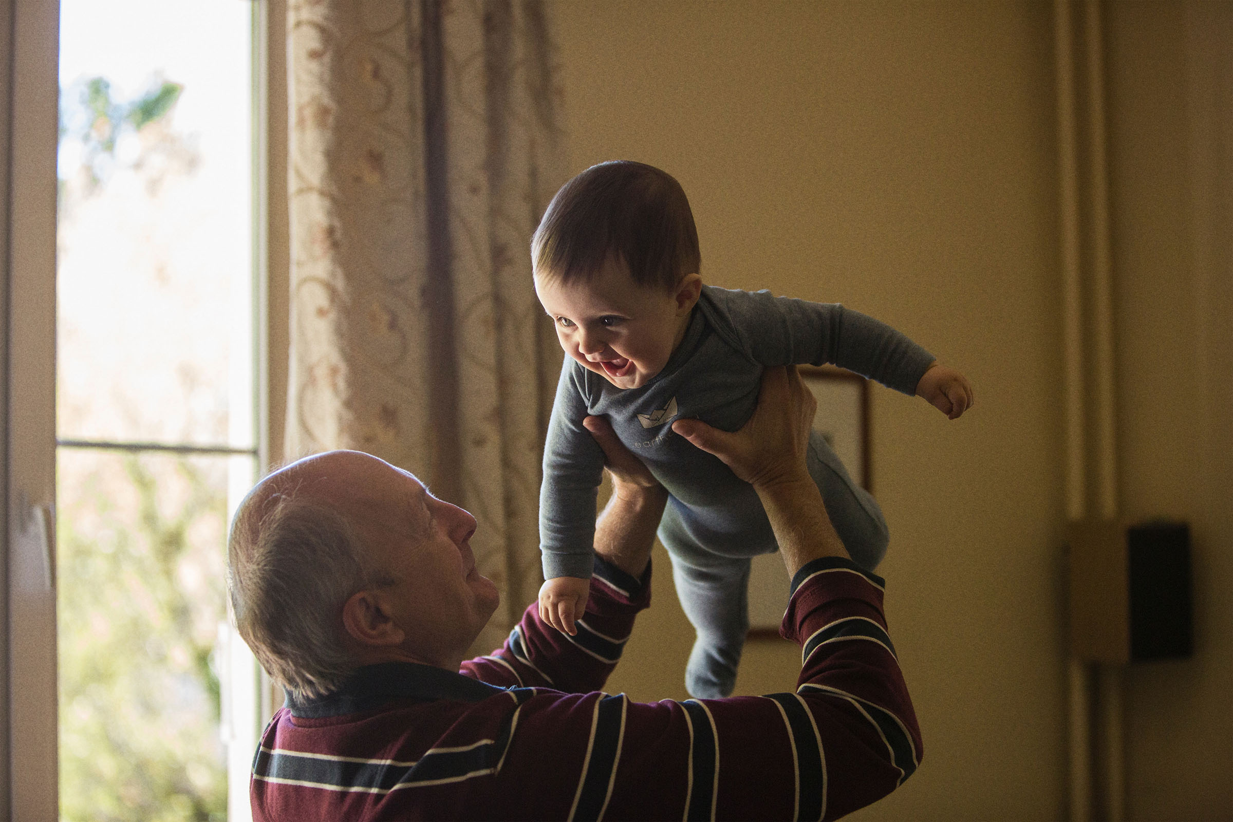 an older man lifting a baby above his head