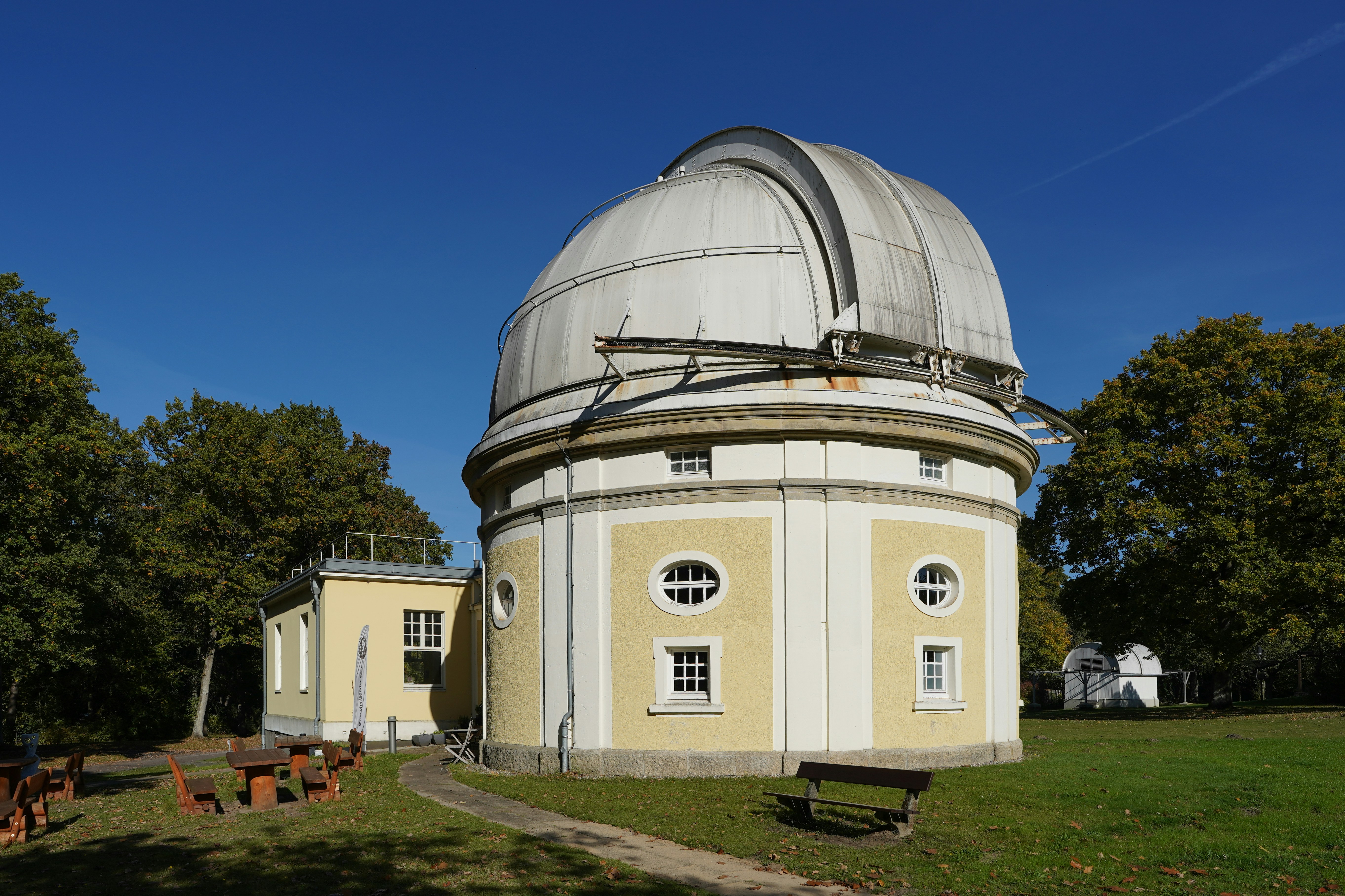 Observatory dome building with trees and clear blue sky.