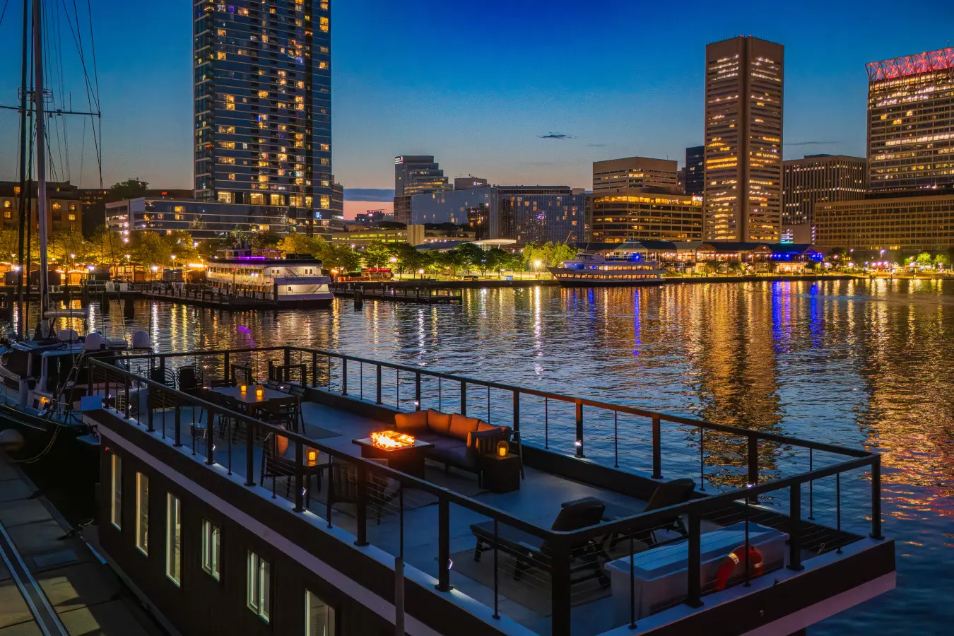 Houseboat rooftop deck overlooking an illuminated city waterfront at dusk