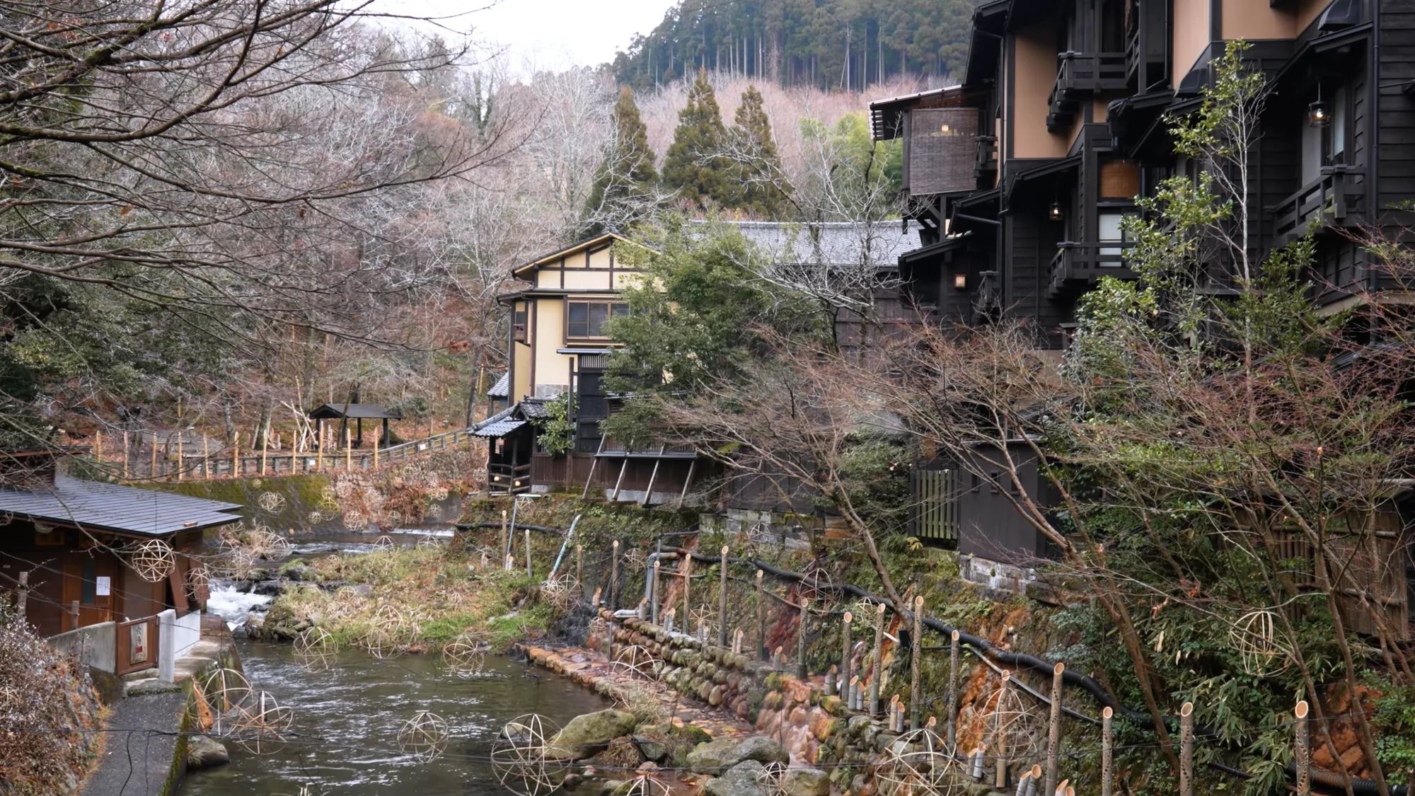 The river running between inns at Kurokawa Onsen among bare winter trees