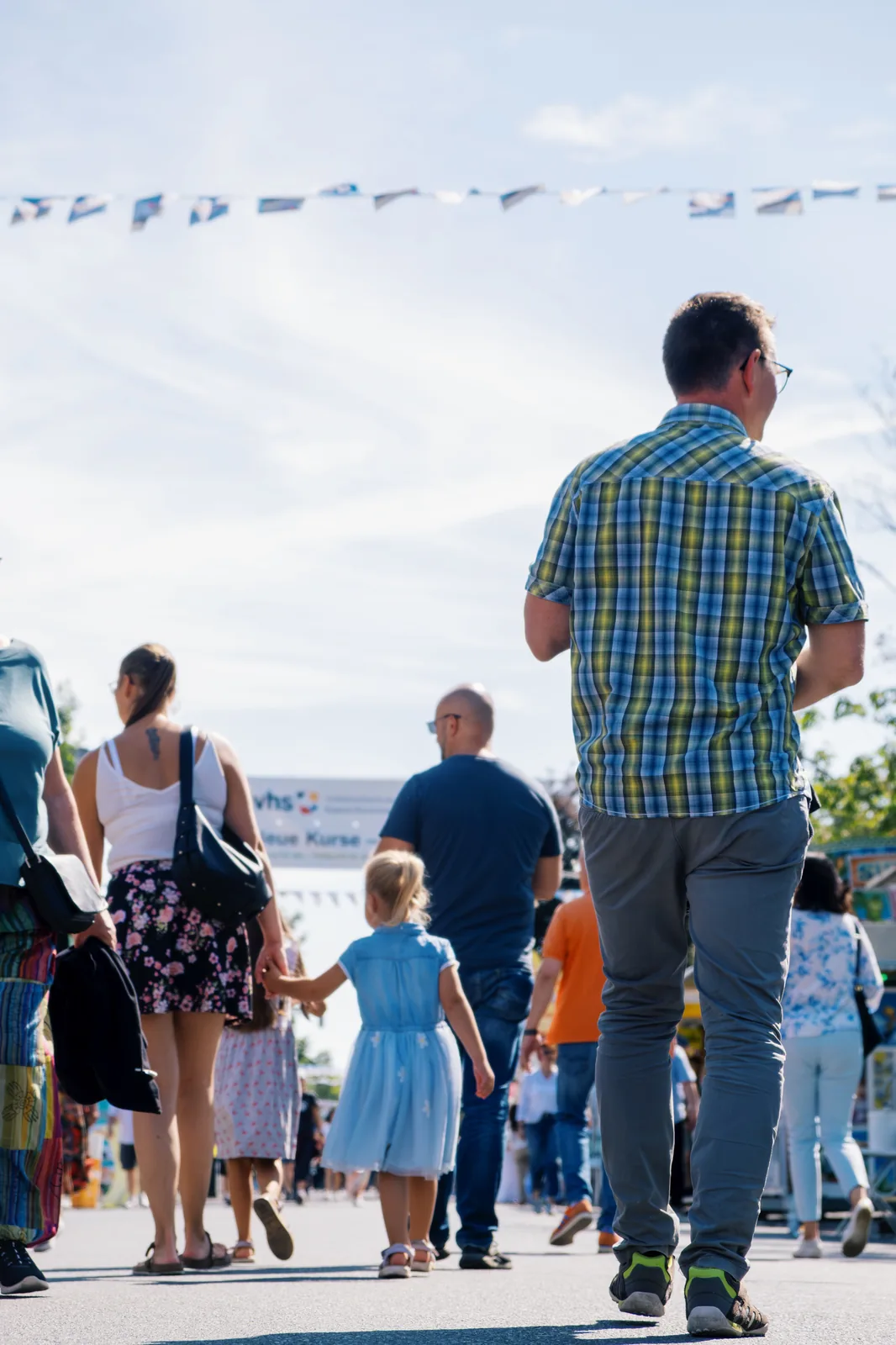 Eine Familie geht unter Wimpelketten die Straße hinunter.