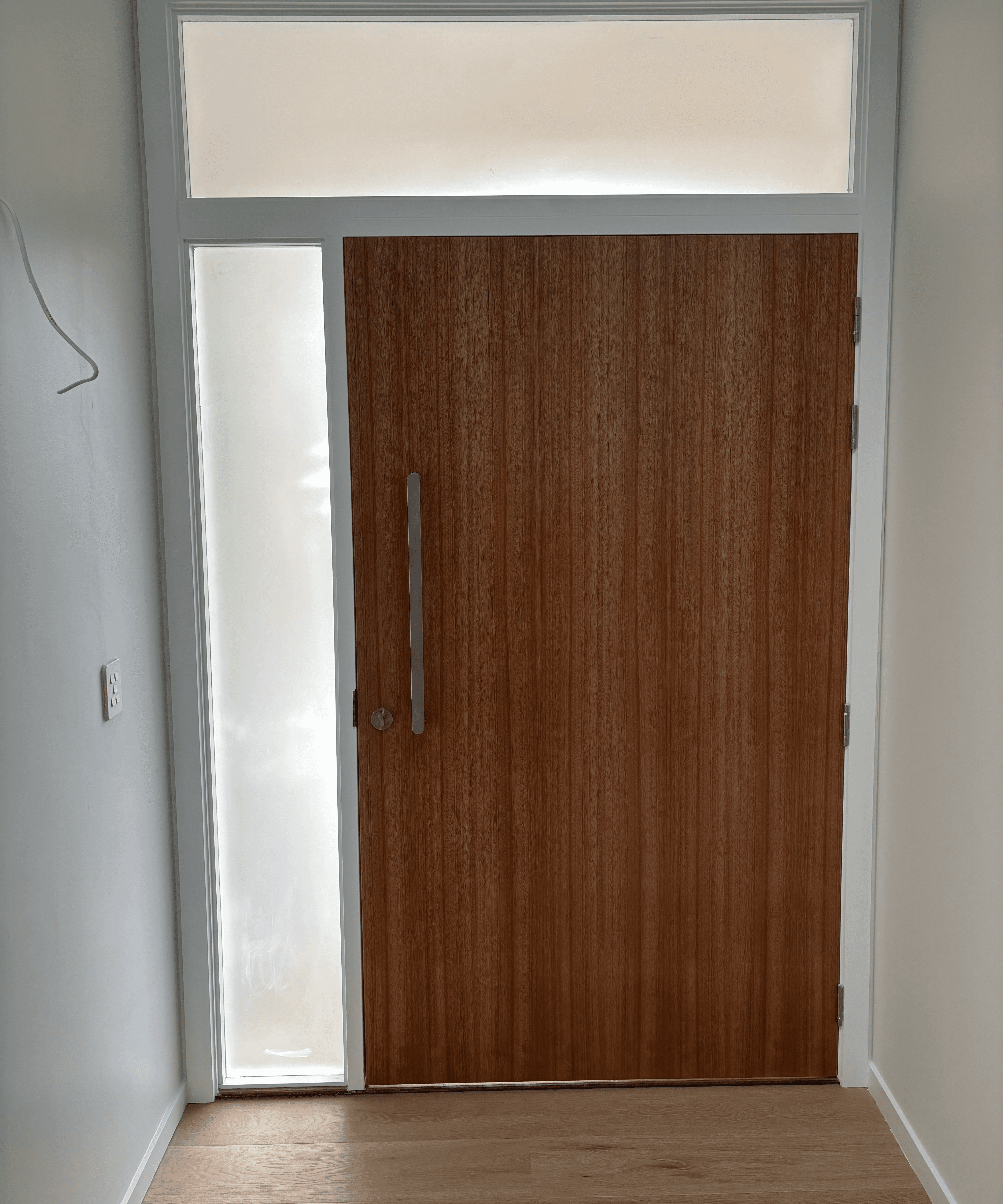 A man and a woman in casual clothing stand face-to-face in a photography studio with a white backdrop. Both have a neutral expression as they engage in conversation.