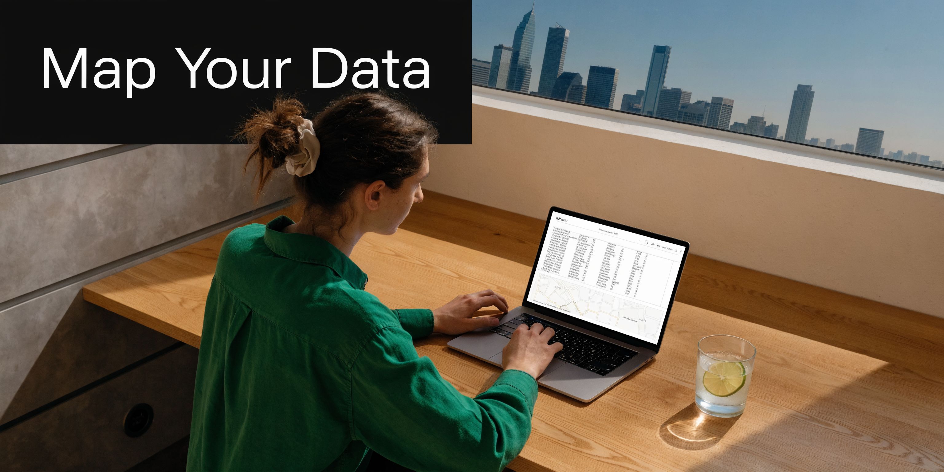 A person working on a laptop displaying address mapping software in a sunny modern office workspace.