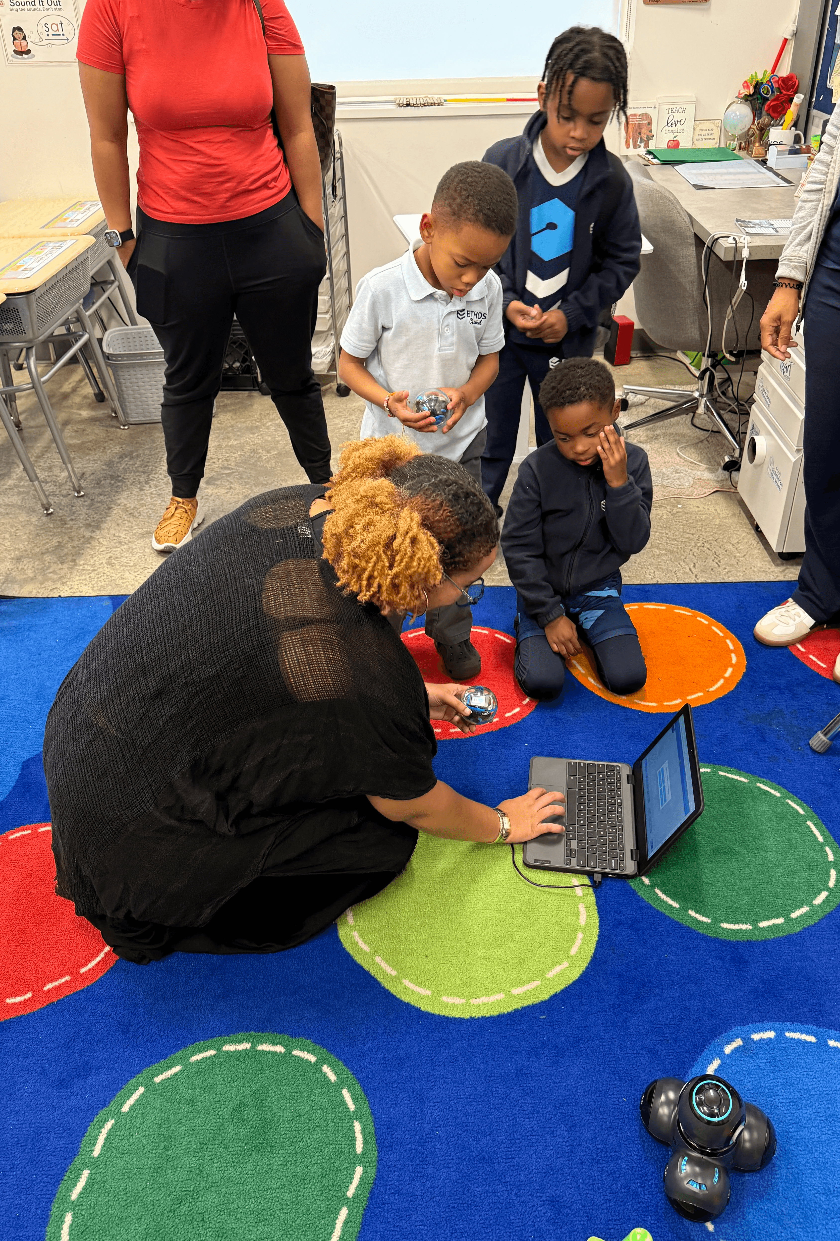 Sitting on the floor with my students as we work through a robotics lesson.
