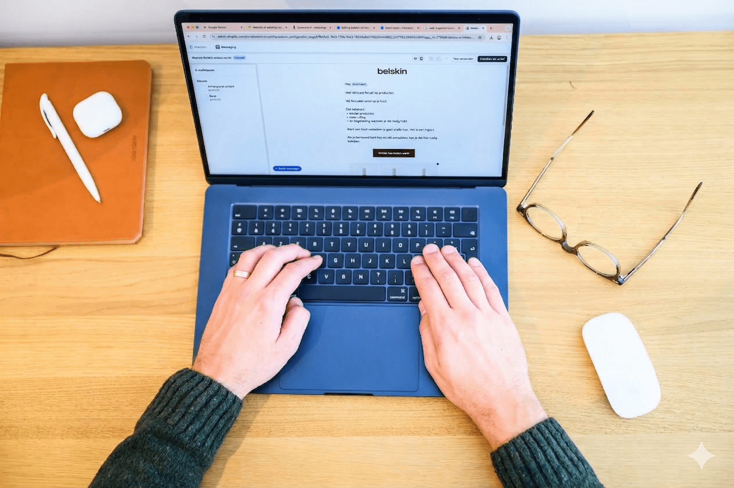 Bovenaanzicht van de handen van Johan op het toetsenbord van de laptop met een email-template op het scherm