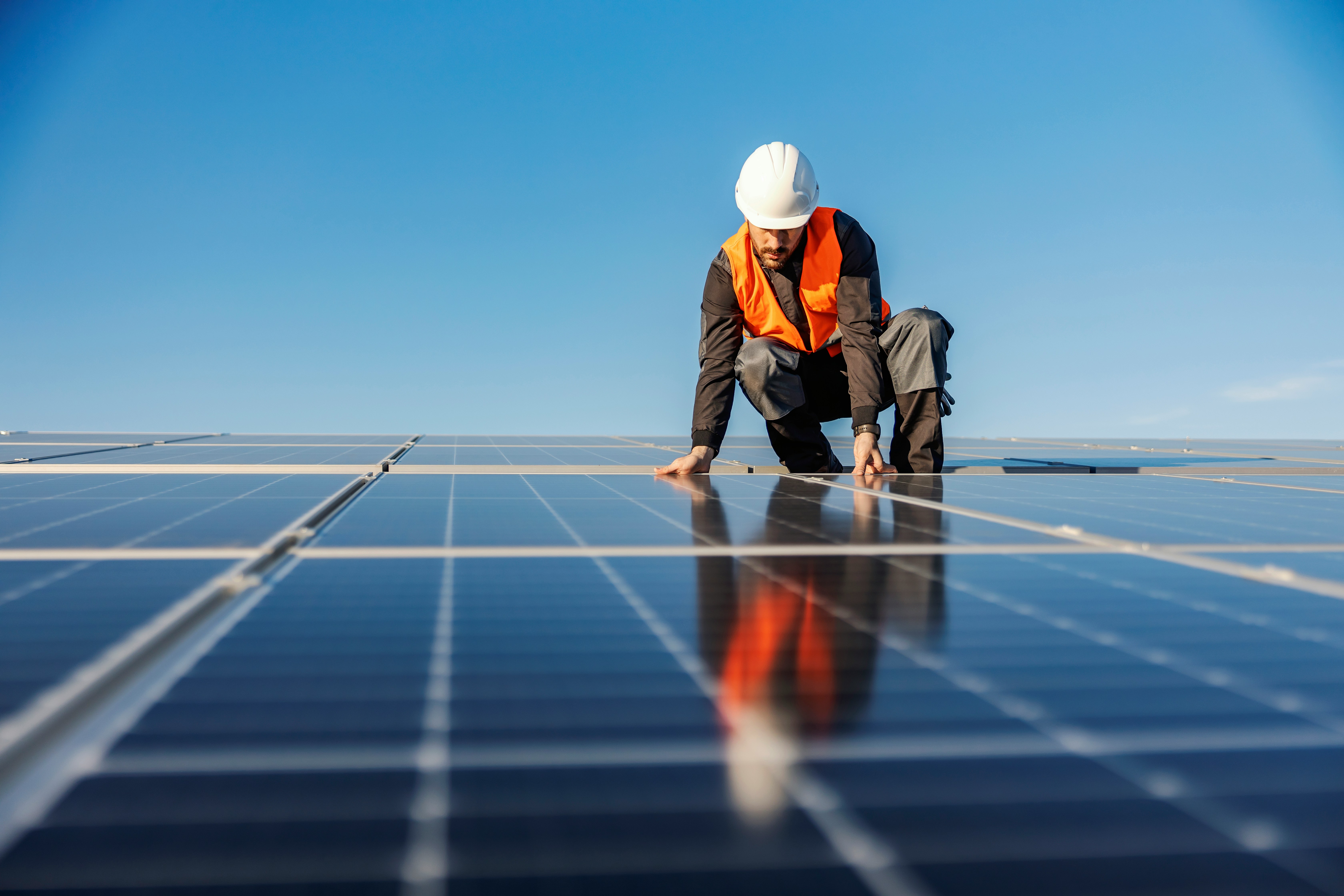 Worker on rooftop inspecting solar panels