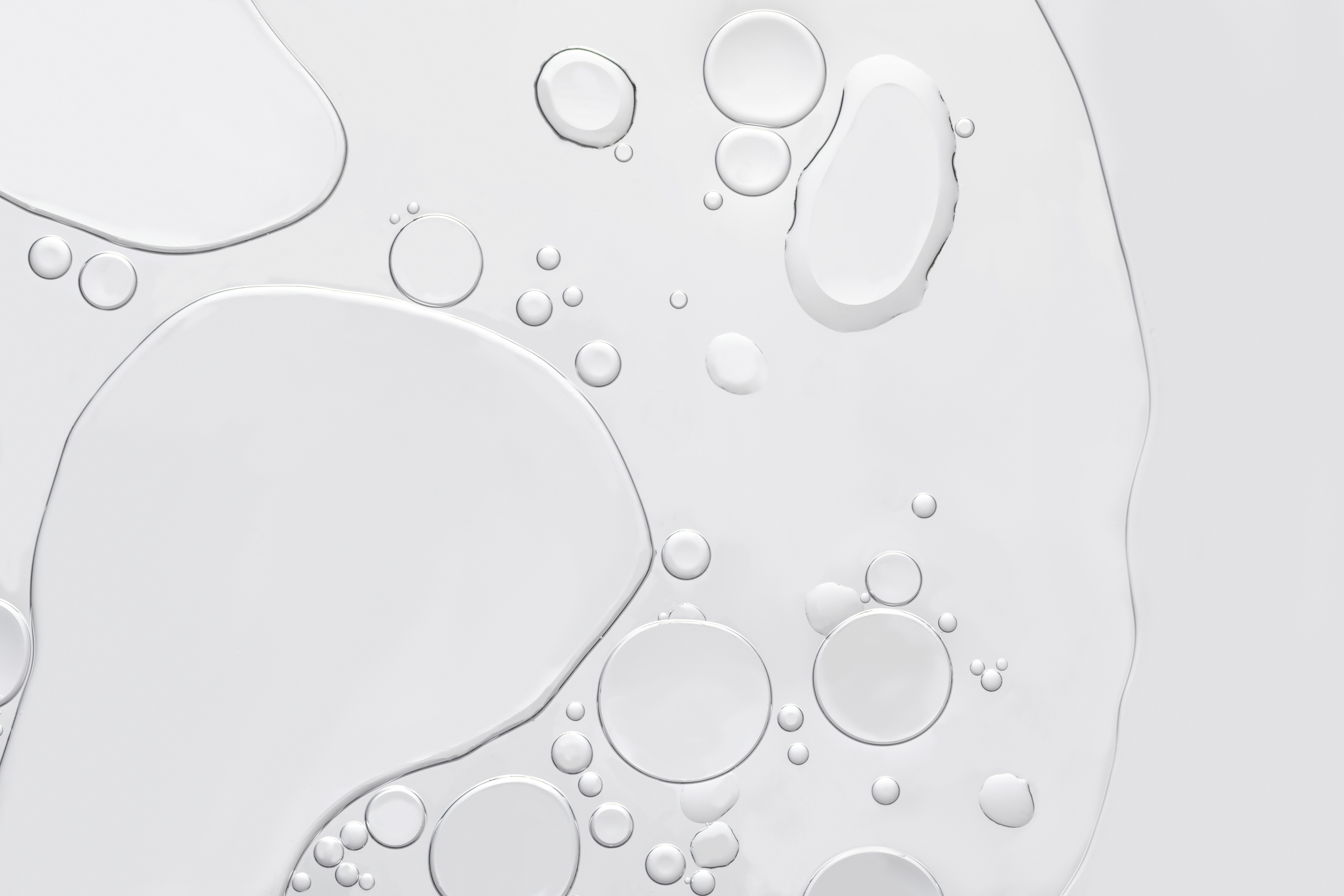 Clear, irregularly shaped liquid bubbles clustered on a white background.