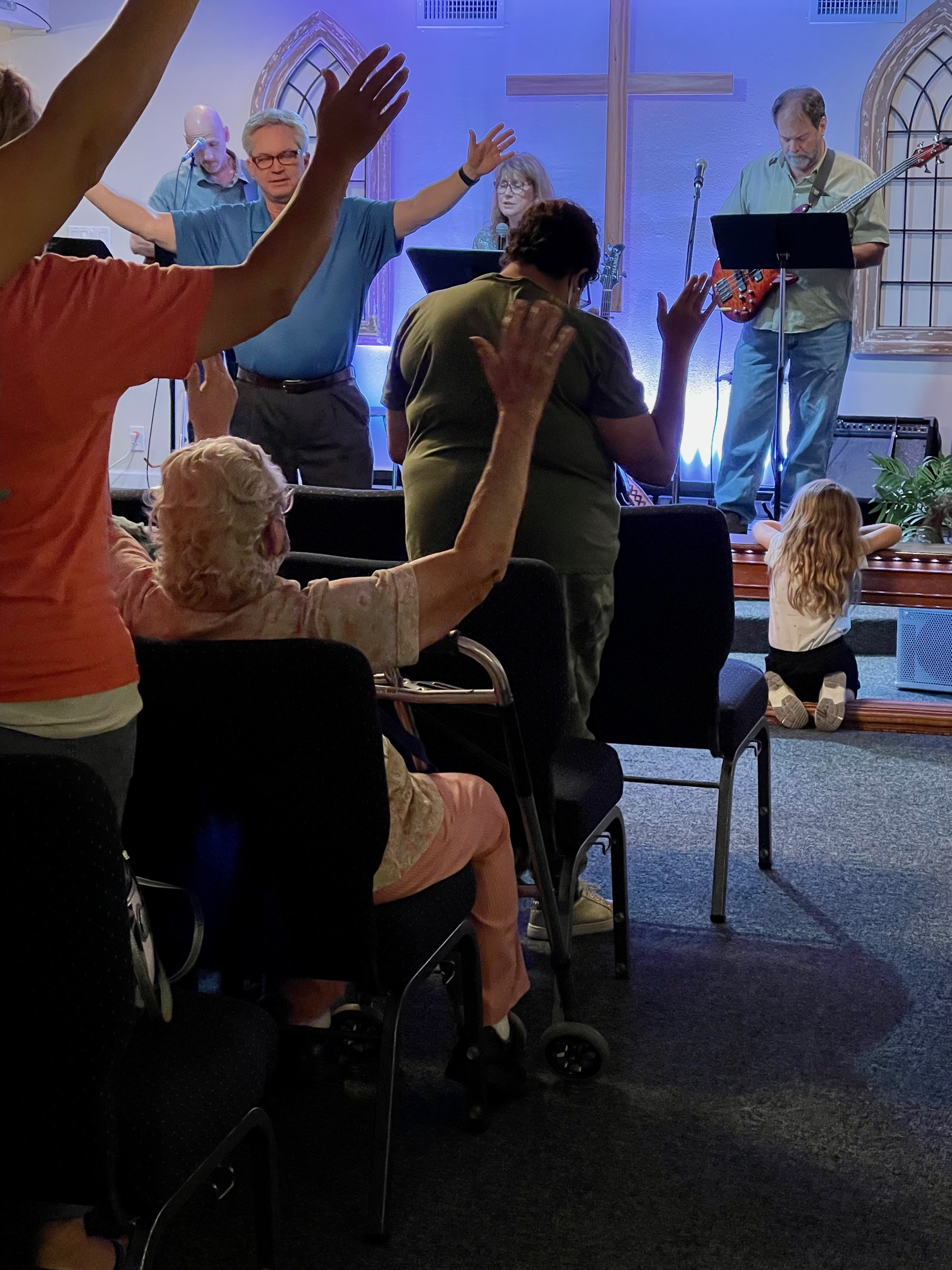 River Church congregation worshiping with raised hands as the worship team leads