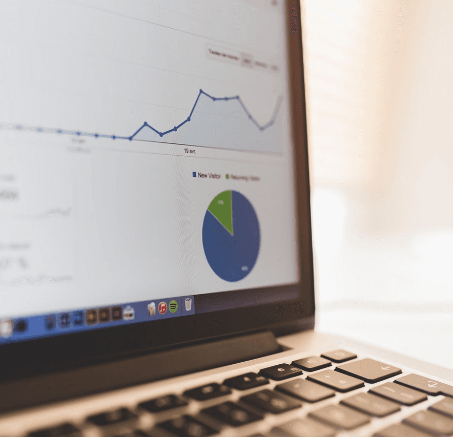 Laptop displaying analytics with a line graph and pie chart on the screen.