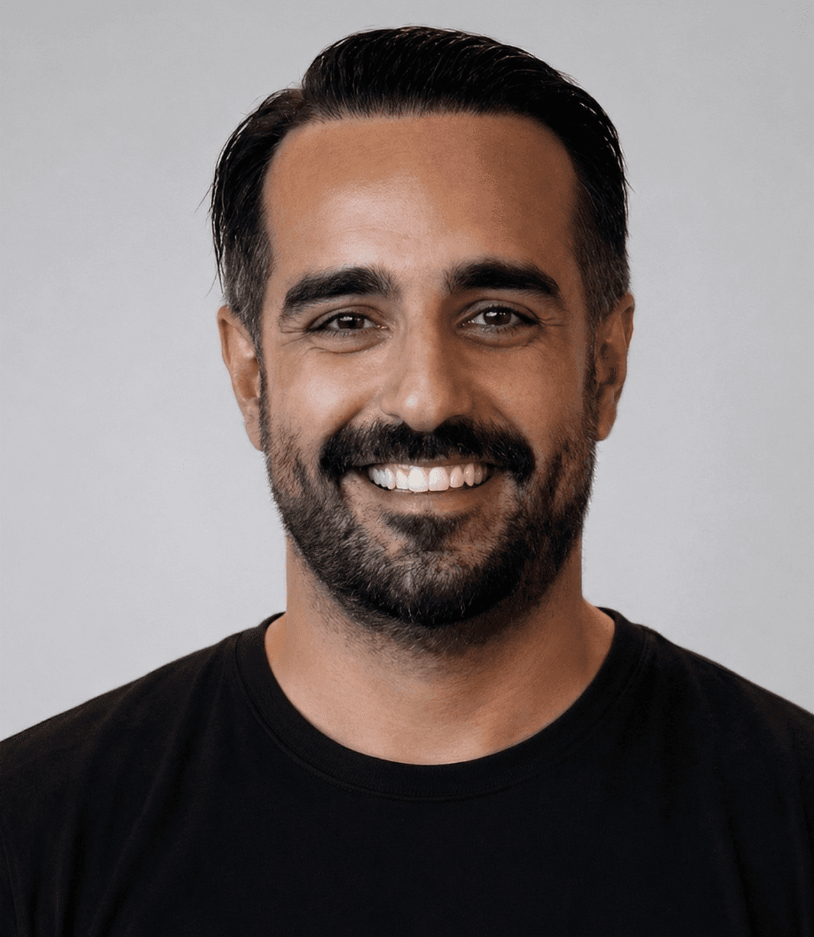 Headshot of WitSpeak founder Fatih Can Yildirim wearing a black shirt against a light background.